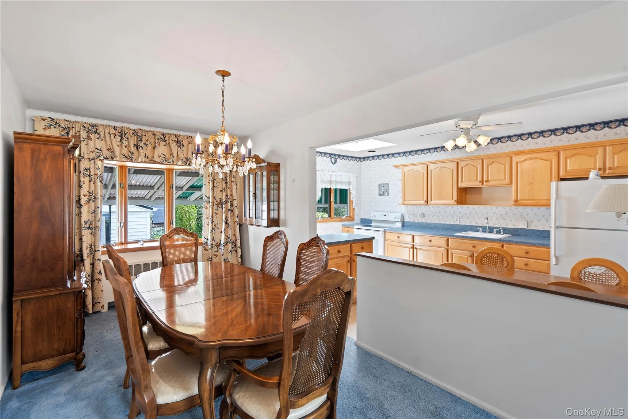 Open-concept living space featuring a dining area with a chandelier and a kitchen with wood-finish cabinetry Open-concept living space featuring a dining area with a chandelier and a kitchen with wood-finish cabinetry