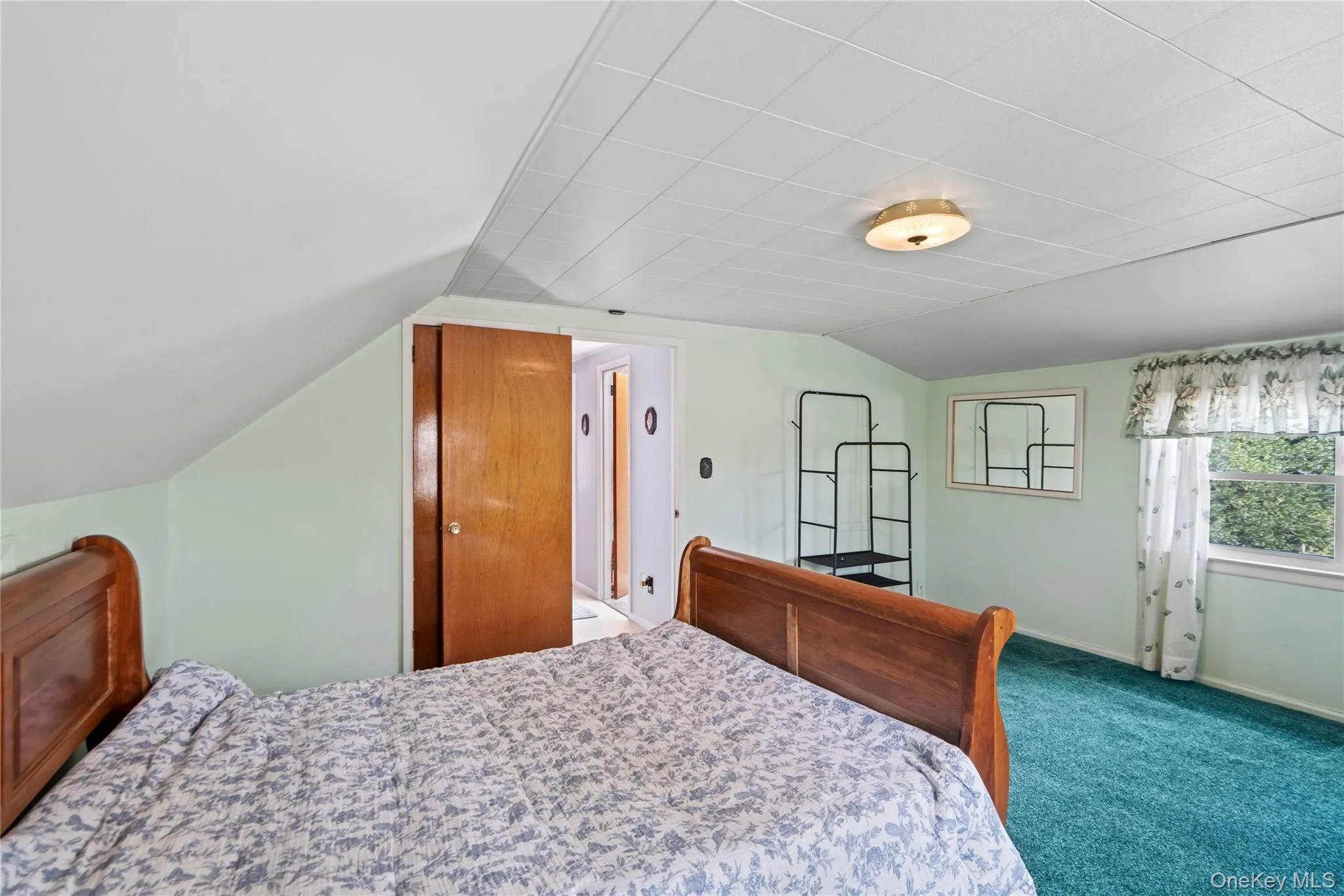 Angled ceiling with a flush-mount light fixture, wood-finish door, and a window providing natural illumination Angled ceiling with a flush-mount light fixture, wood-finish door, and a window providing natural illumination