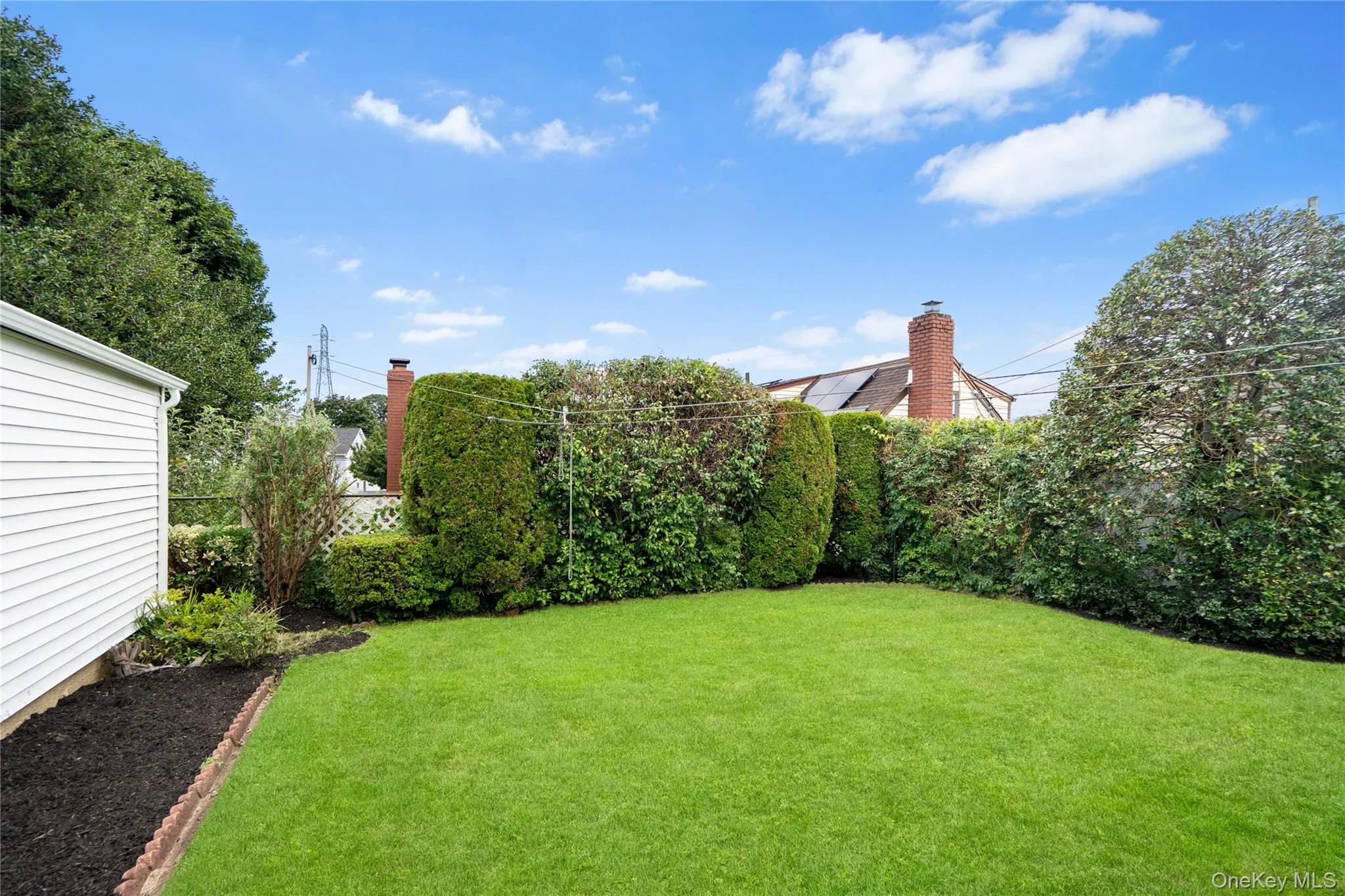 Expansive lawn area with mature hedges and a white siding structure Expansive lawn area with mature hedges and a white siding structure