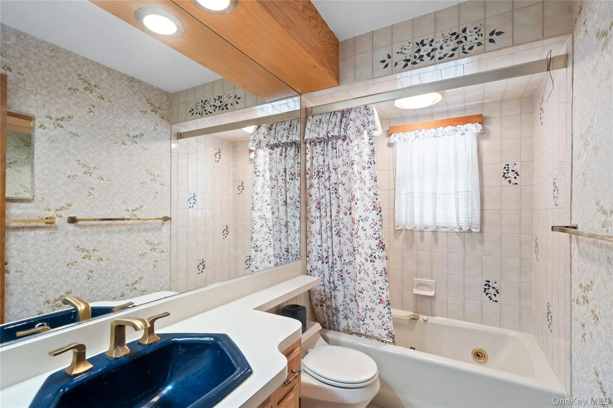 Full-width vanity mirror, recessed ceiling lighting, built-in bathtub, and tiled shower surround Full-width vanity mirror, recessed ceiling lighting, built-in bathtub, and tiled shower surround