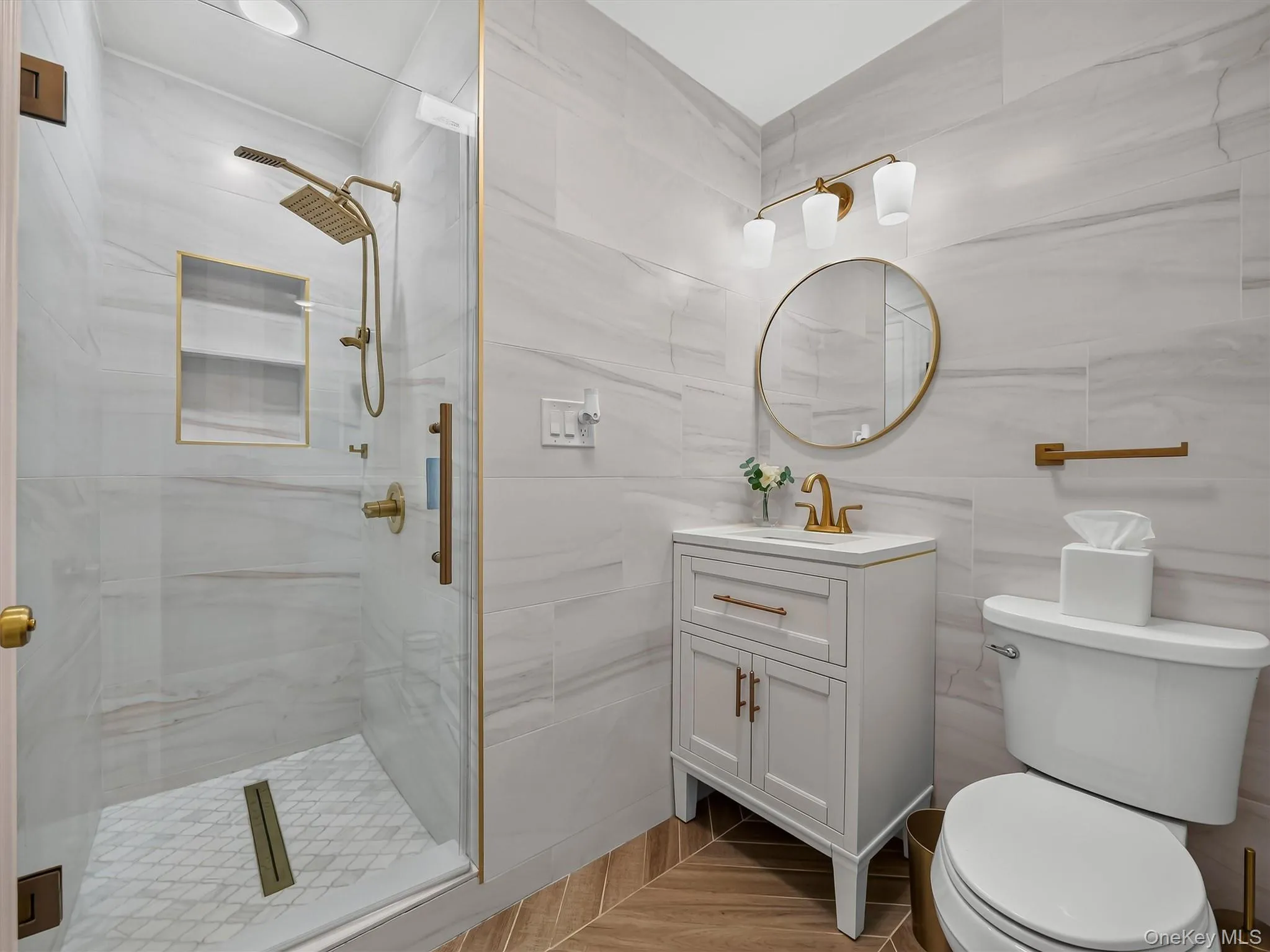 Glass-enclosed shower with a rainfall showerhead and handheld sprayer, complemented by a built-in shower niche Glass-enclosed shower with a rainfall showerhead and handheld sprayer, complemented by a built-in shower niche