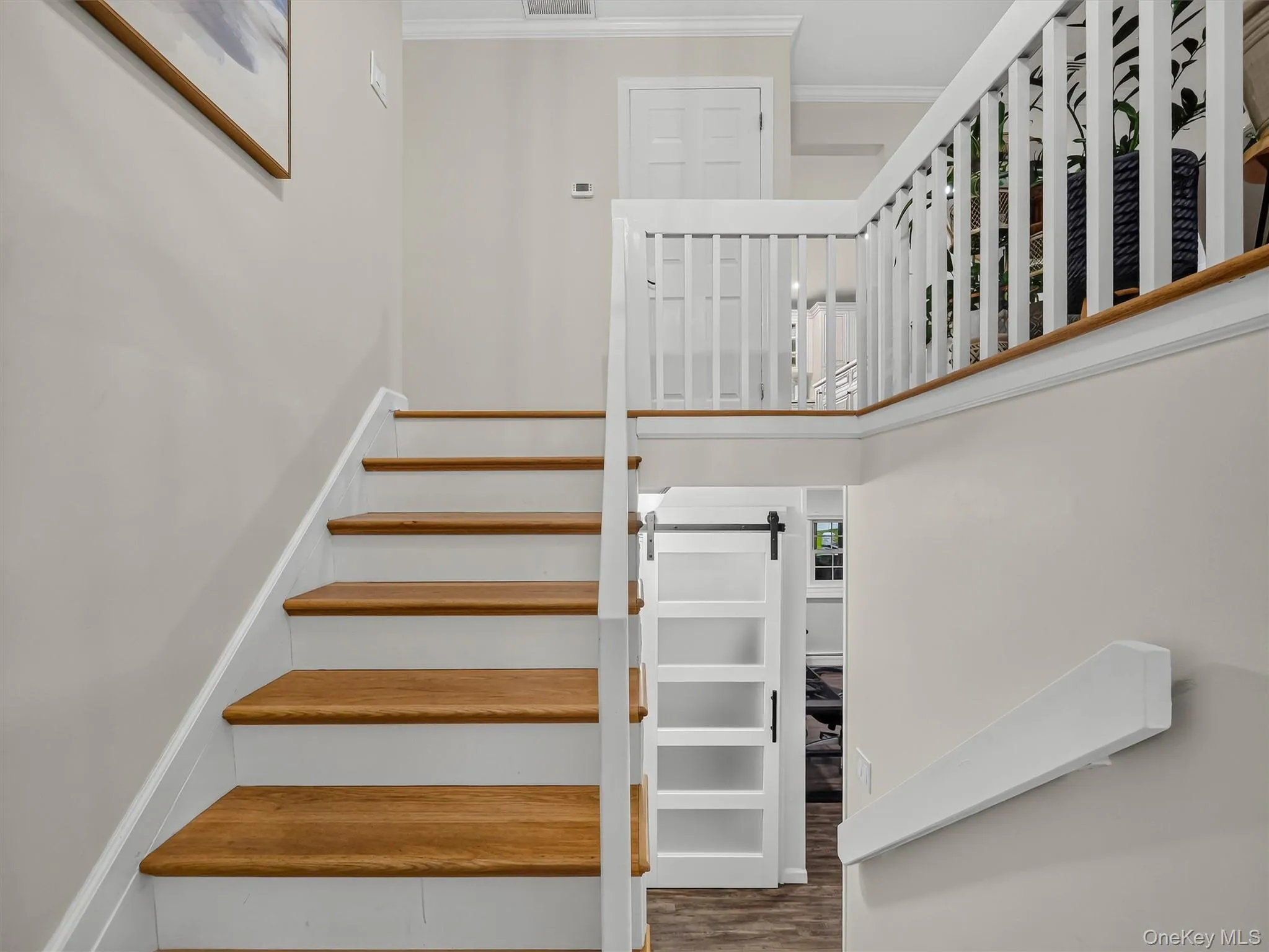 Hardwood stair treads, white risers, white railing, white balusters, and a sliding barn door with opaque panels Hardwood stair treads, white risers, white railing, white balusters, and a sliding barn door with opaque panels