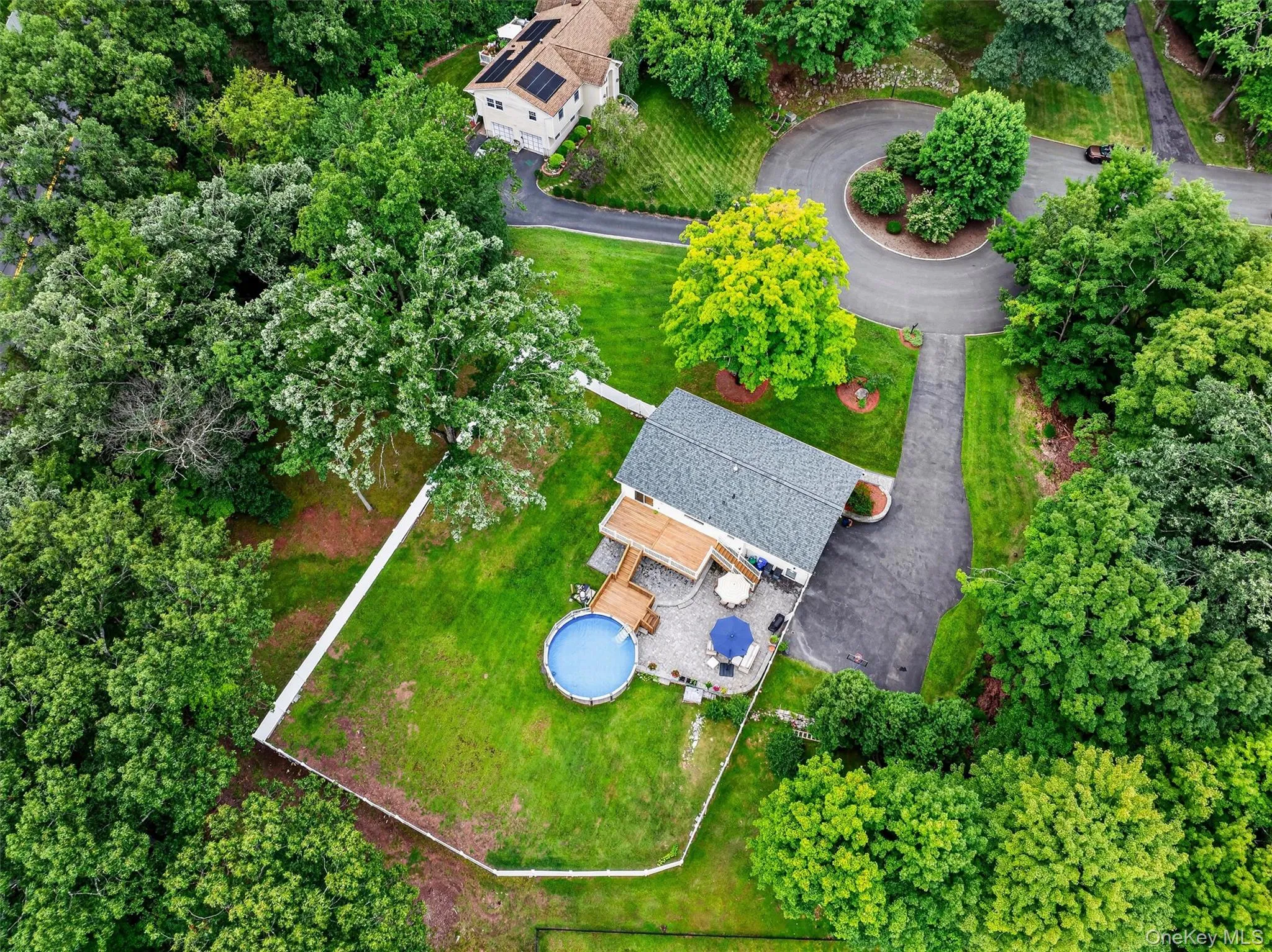 Expansive lot featuring mature trees, a private driveway, a fenced lawn area, and a paved patio Expansive lot featuring mature trees, a private driveway, a fenced lawn area, and a paved patio