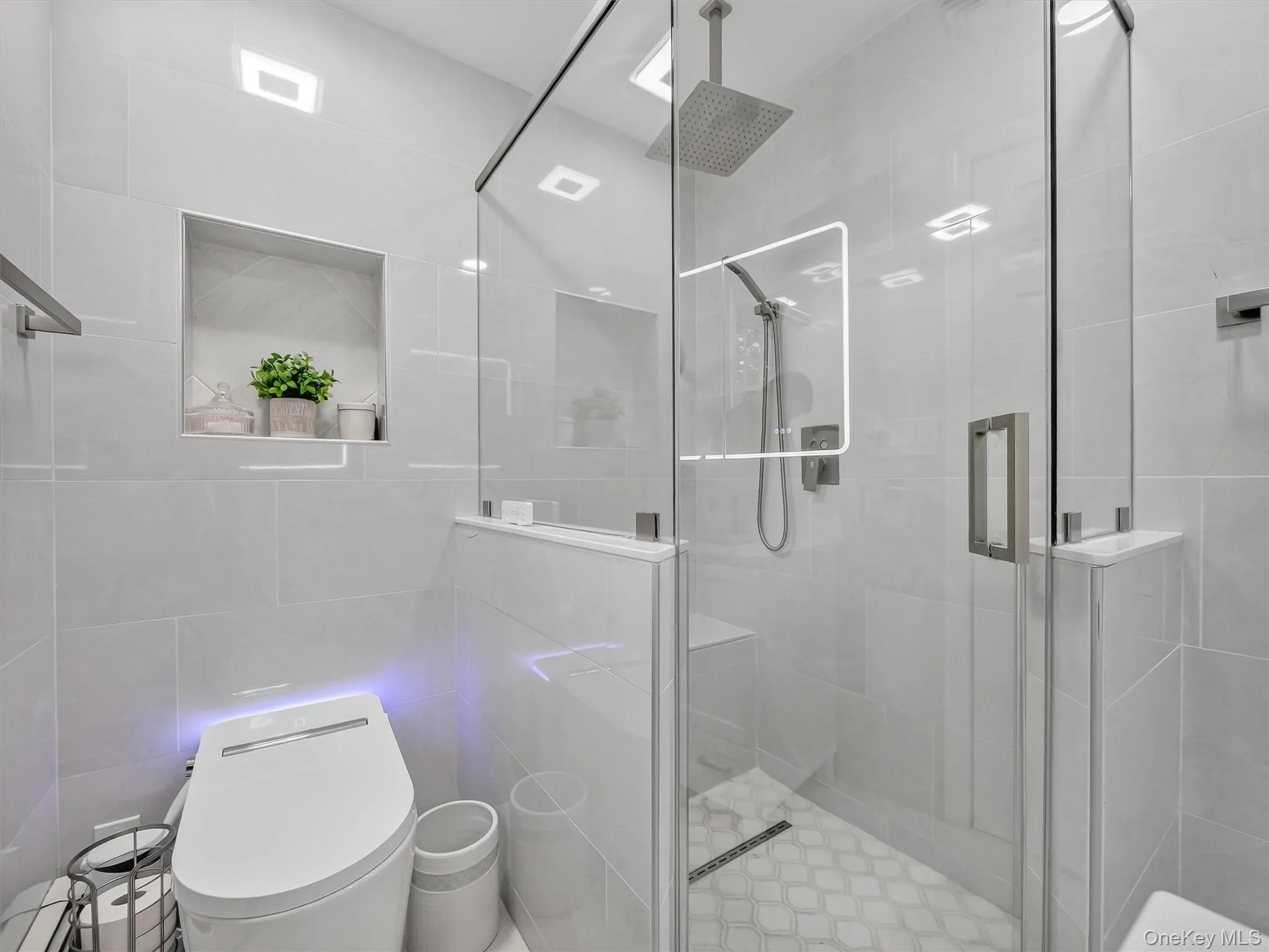 Frameless glass shower enclosure with a rain shower head, hand-held shower, and patterned tile flooring Frameless glass shower enclosure with a rain shower head, hand-held shower, and patterned tile flooring