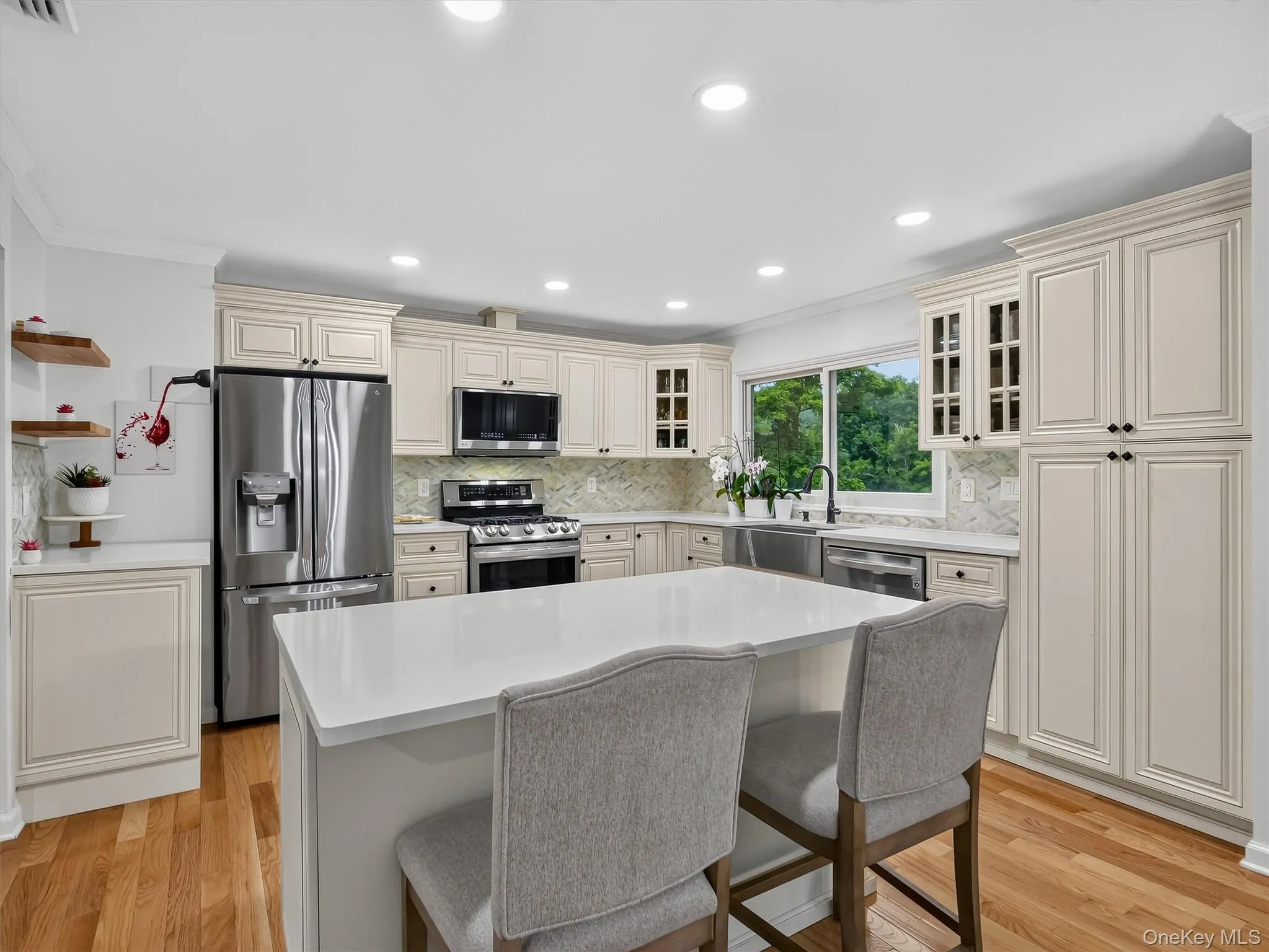 Kitchen with wood-finish flooring, recessed lighting, a central island, and light-toned cabinetry Kitchen with wood-finish flooring, recessed lighting, a central island, and light-toned cabinetry