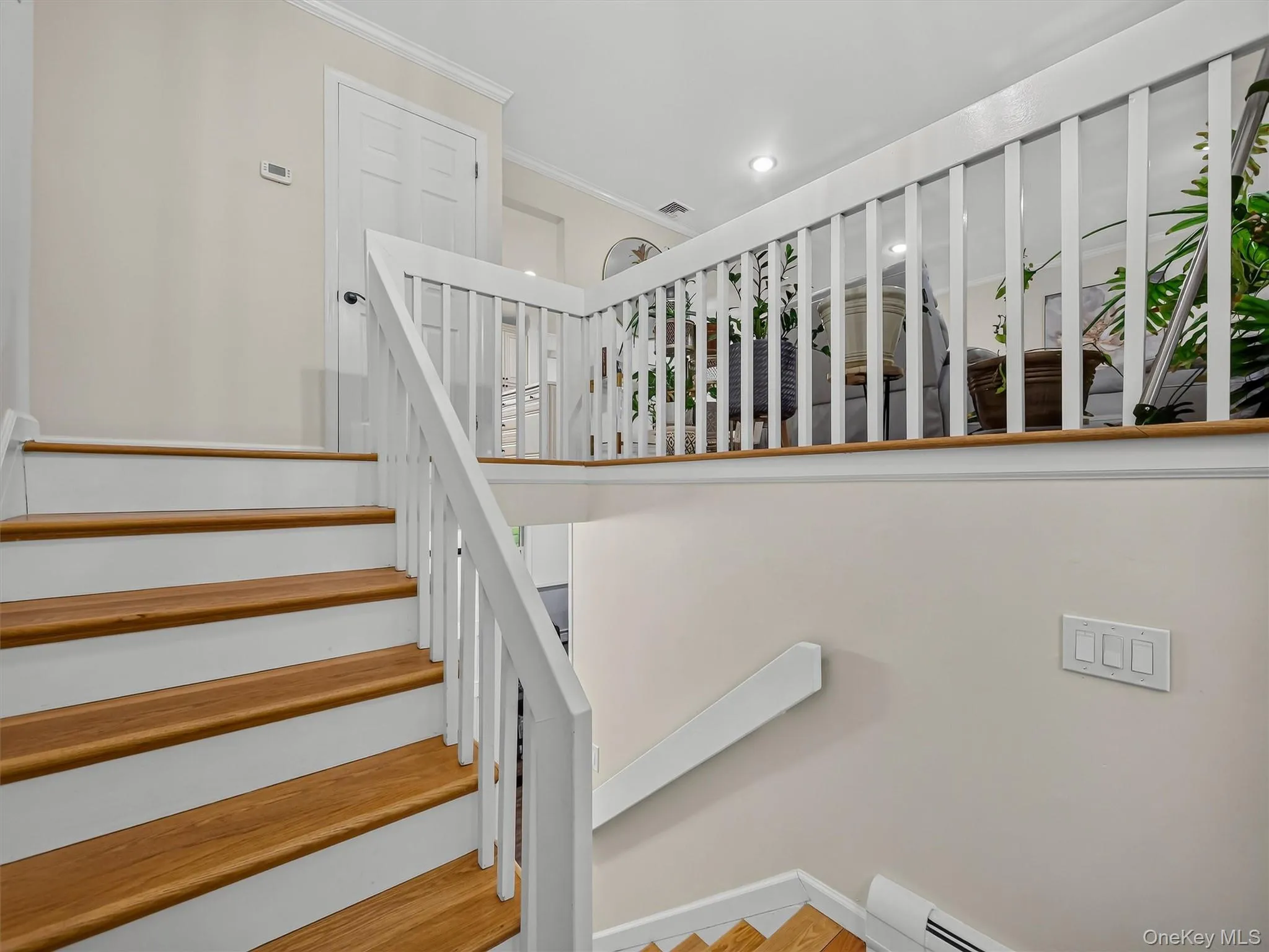 Hardwood stair treads with painted risers, white railing and balusters, painted interior door, recessed lighting, and wall-mounted light switches Hardwood stair treads with painted risers, white railing and balusters, painted interior door, recessed lighting, and wall-mounted light switches