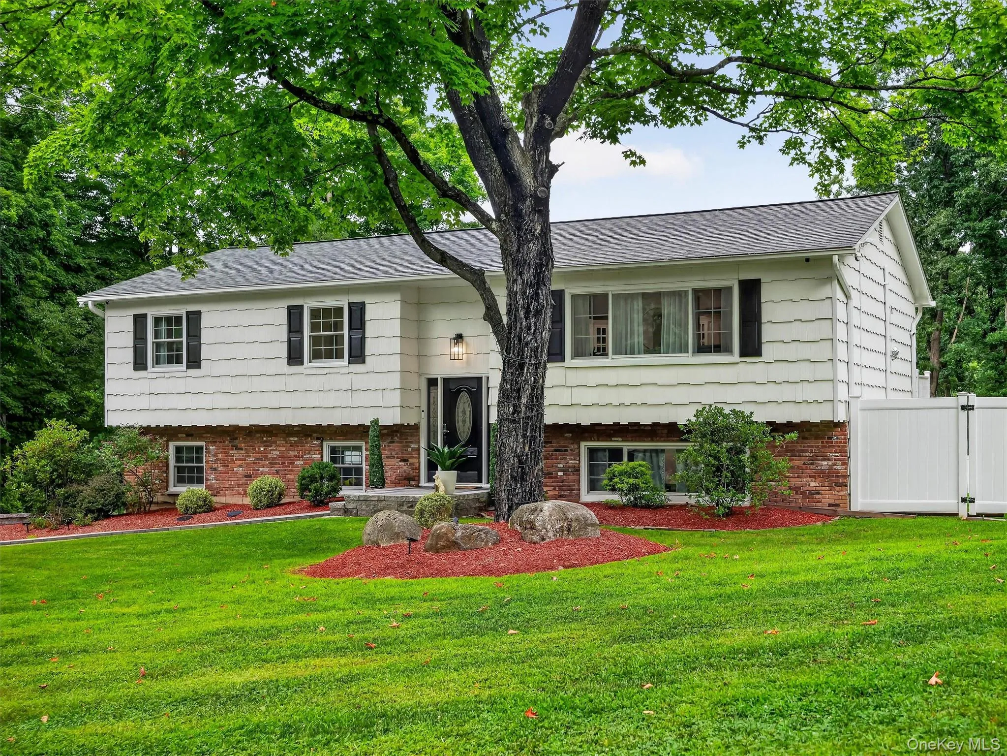 Split-level residence featuring white siding and a brick lower level Split-level residence featuring white siding and a brick lower level