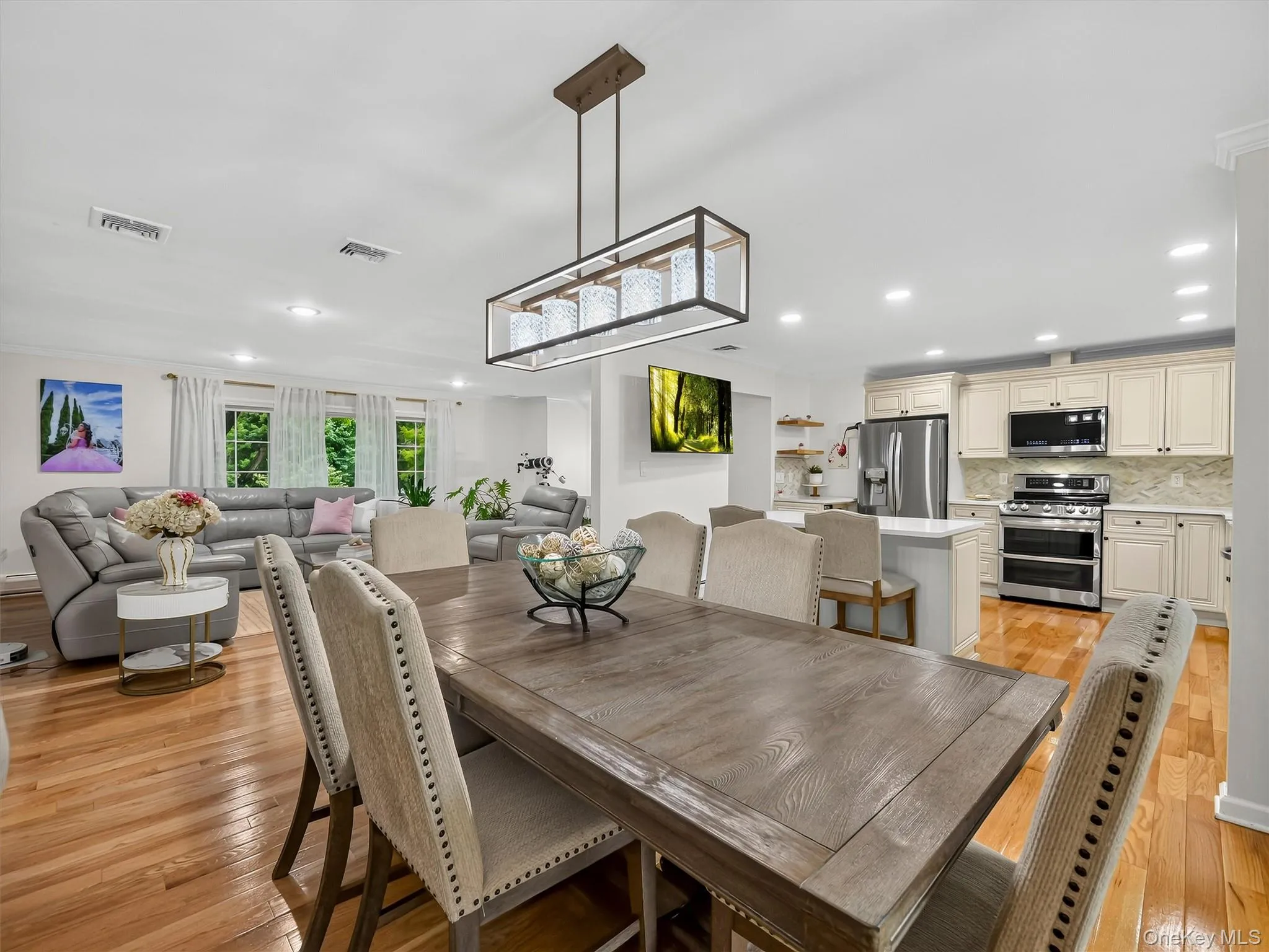 Open-concept living space with wood-finish flooring, recessed lighting, and a linear chandelier Open-concept living space with wood-finish flooring, recessed lighting, and a linear chandelier