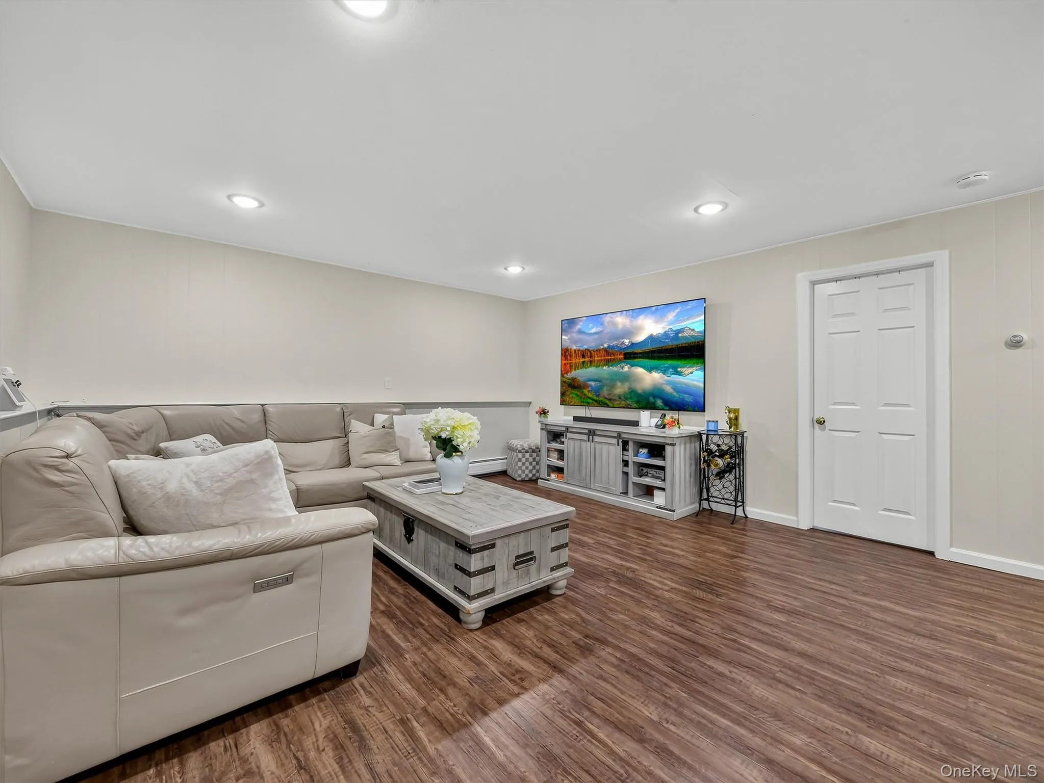 Recessed lighting, wood-finish flooring, two-tone wall treatment, white interior door, media console Recessed lighting, wood-finish flooring, two-tone wall treatment, white interior door, media console