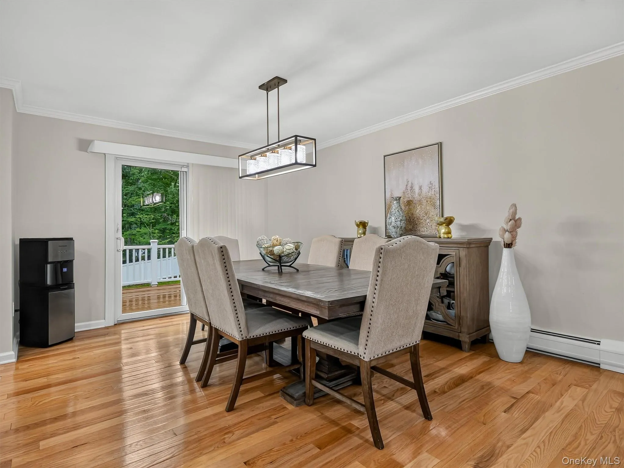 Hardwood flooring, crown molding, modern linear chandelier, glass sliding door, and white railing Hardwood flooring, crown molding, modern linear chandelier, glass sliding door, and white railing