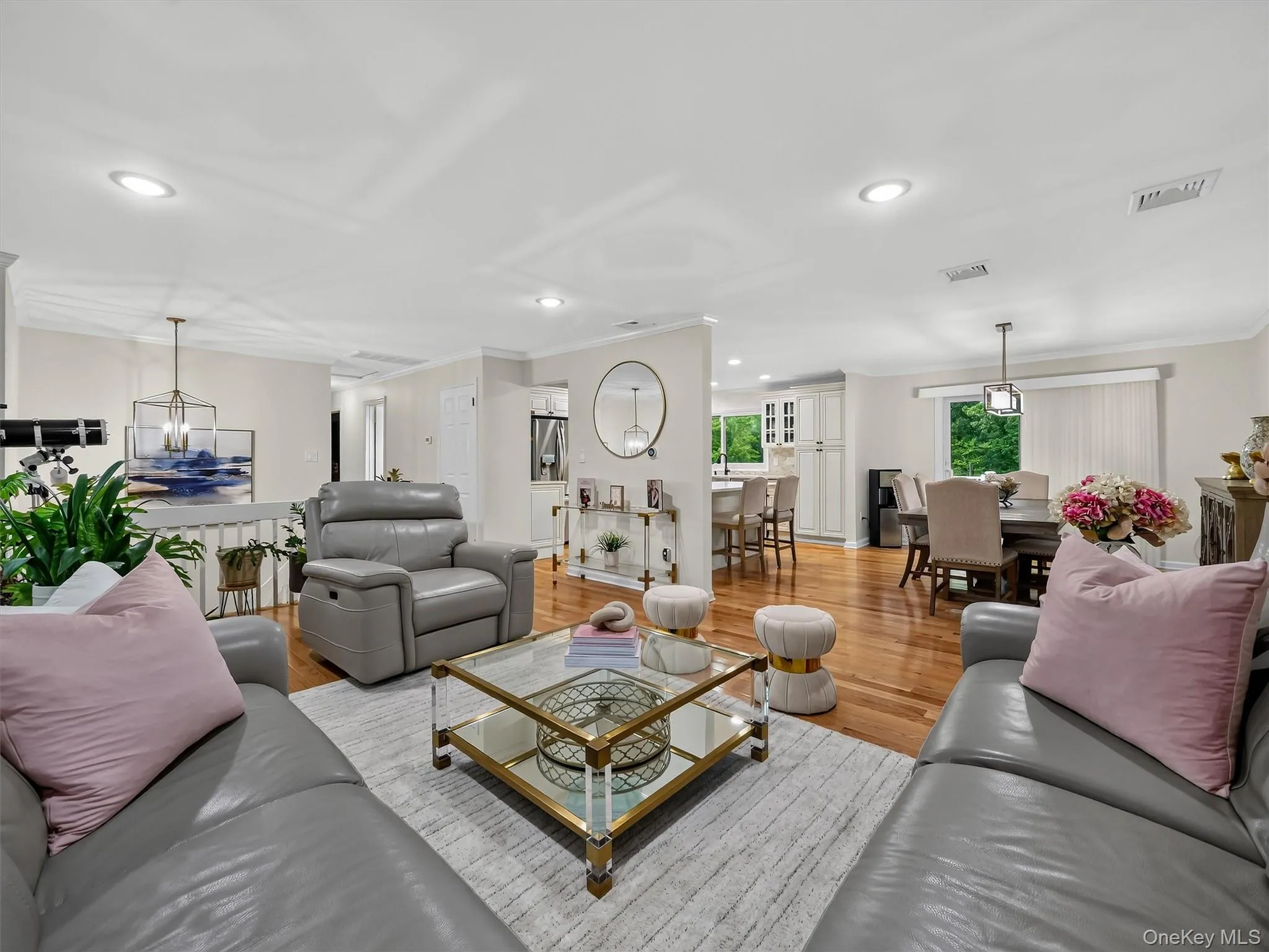 Open-concept living space featuring wood-finish flooring, recessed lighting, and a dining area with a contemporary chandelier Open-concept living space featuring wood-finish flooring, recessed lighting, and a dining area with a contemporary chandelier