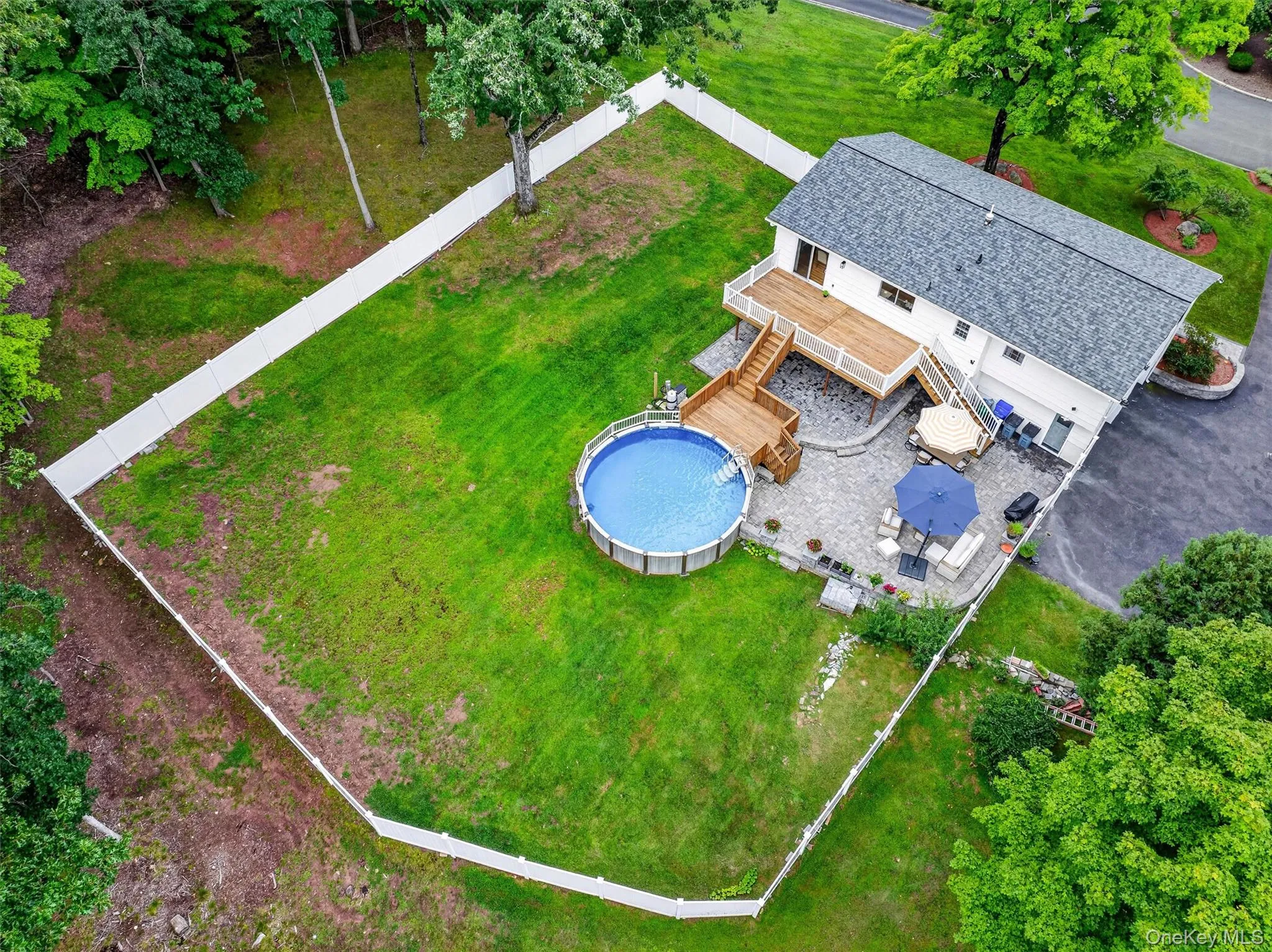 Fenced yard featuring a large lawn, above-ground pool, and wood deck Fenced yard featuring a large lawn, above-ground pool, and wood deck