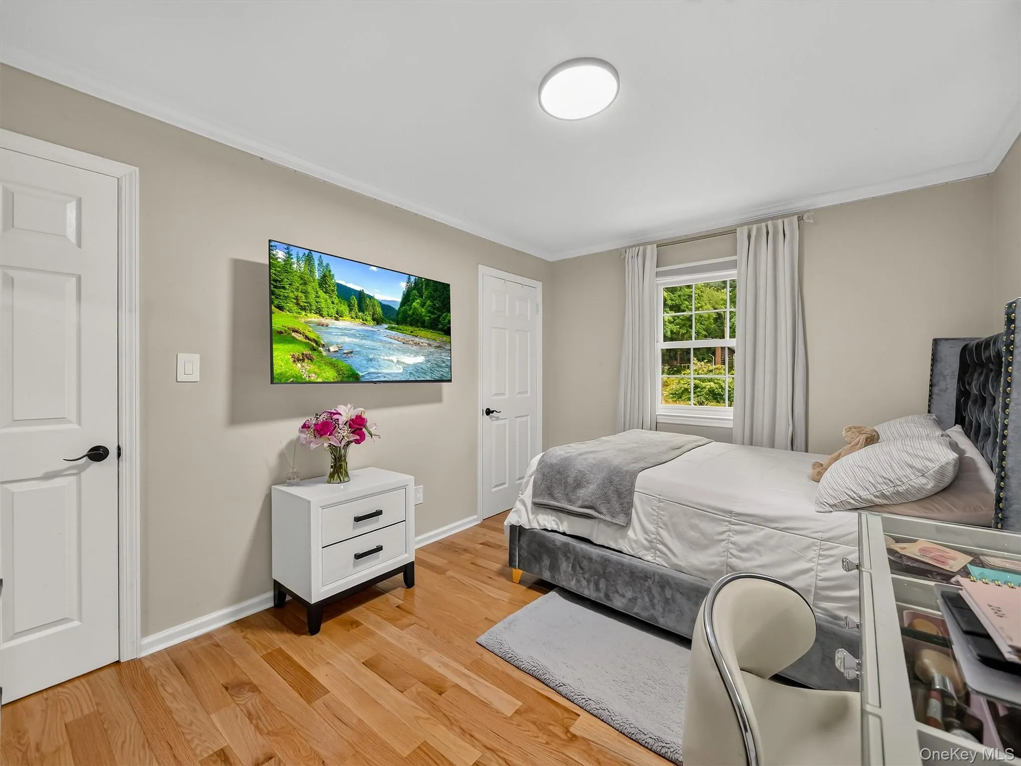 Hardwood flooring, painted walls, crown molding, white paneled doors with black hardware, and a window with natural light Hardwood flooring, painted walls, crown molding, white paneled doors with black hardware, and a window with natural light