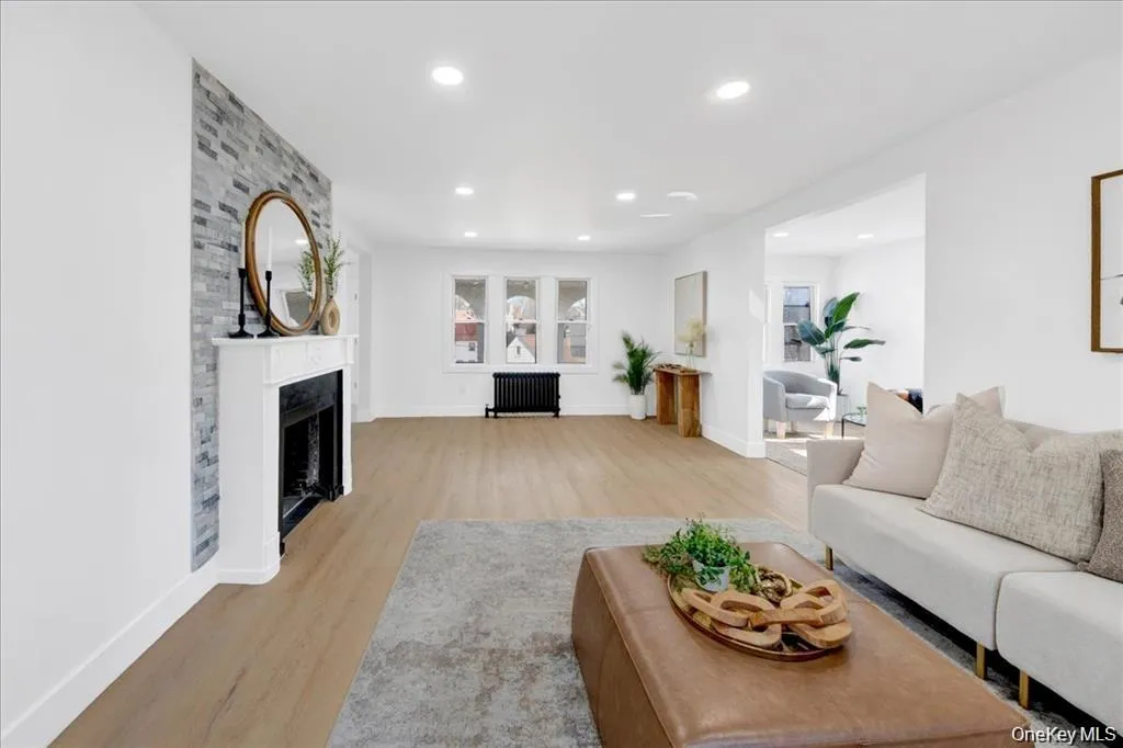 Recessed lighting, wood-finish flooring, white walls, and a stone accent wall with a fireplace Recessed lighting, wood-finish flooring, white walls, and a stone accent wall with a fireplace