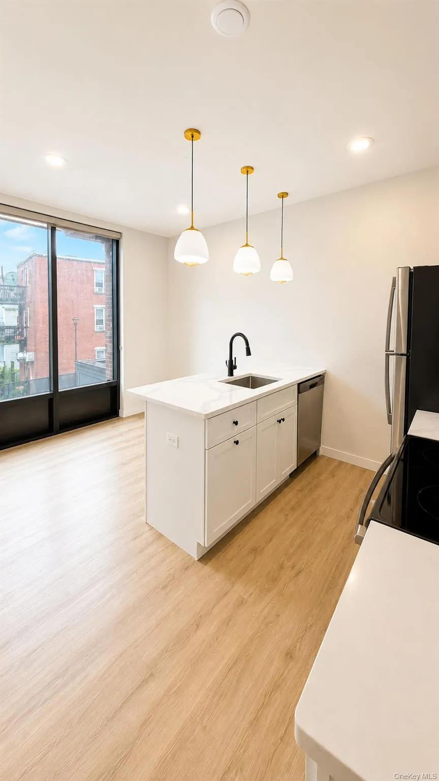 Kitchen featuring a center island with a sink, white cabinetry, and a light-toned wood-finish floor Kitchen featuring a center island with a sink, white cabinetry, and a light-toned wood-finish floor