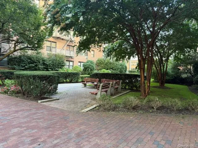 Brick paver patio with a stone border, mature trees, manicured hedges, and grassy areas Brick paver patio with a stone border, mature trees, manicured hedges, and grassy areas