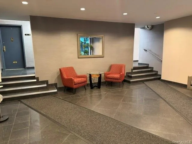 Recessed ceiling lighting, dark tile flooring, staircase with metal handrail, textured wall covering, and a dark entry door with brass hardware Recessed ceiling lighting, dark tile flooring, staircase with metal handrail, textured wall covering, and a dark entry door with brass hardware