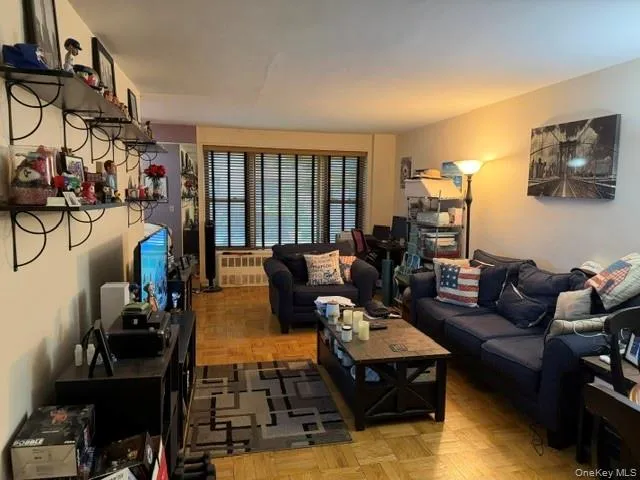 Wood-finish flooring throughout, featuring a large window with horizontal blinds, built-in wall shelving, and a wall-mounted display cabinet Wood-finish flooring throughout, featuring a large window with horizontal blinds, built-in wall shelving, and a wall-mounted display cabinet