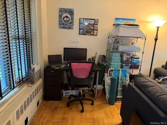 Hardwood parquet flooring, window with blinds, and a built-in radiator cover Hardwood parquet flooring, window with blinds, and a built-in radiator cover