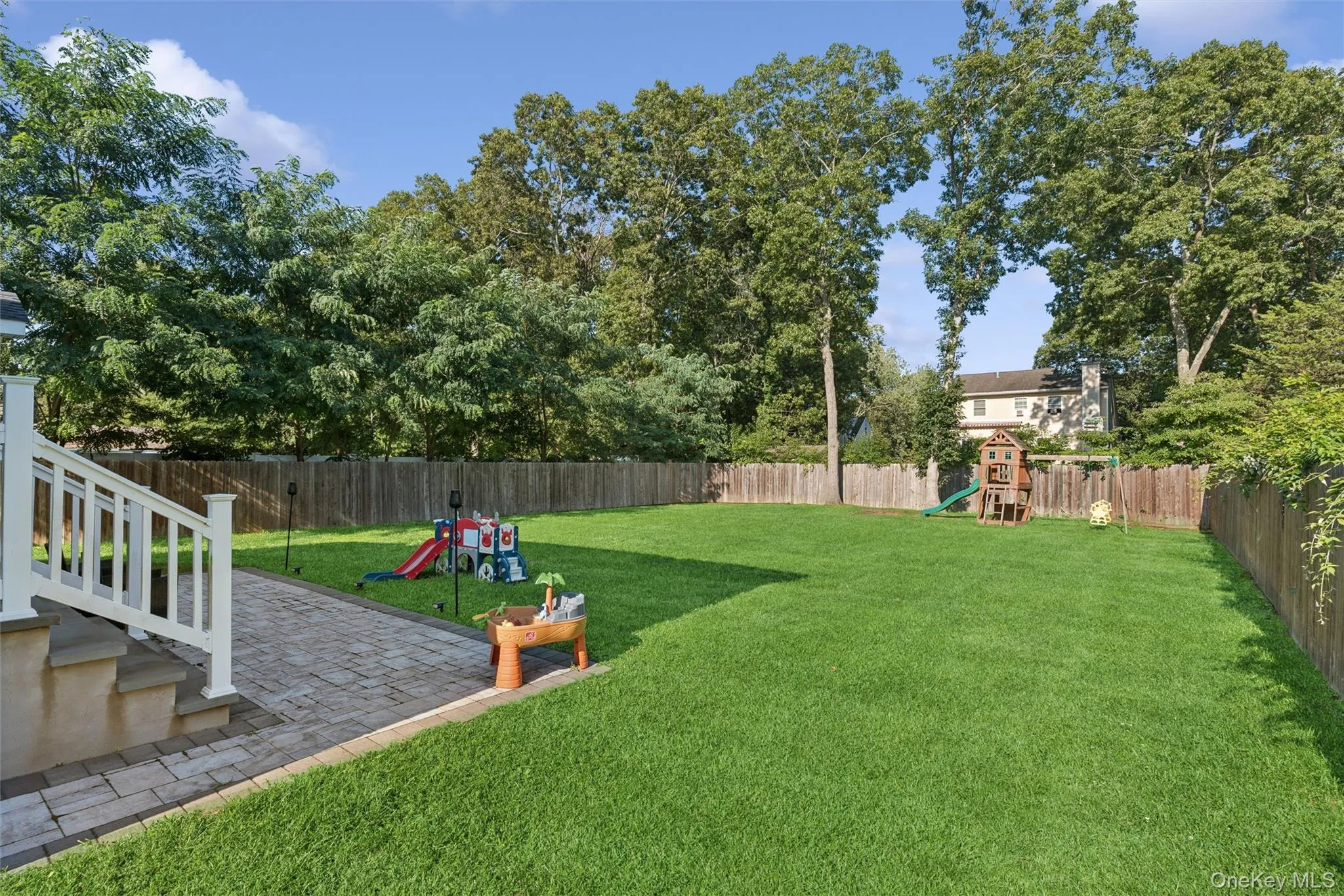 Expansive backyard with a manicured lawn, complete privacy fencing, and mature perimeter trees Expansive backyard with a manicured lawn, complete privacy fencing, and mature perimeter trees