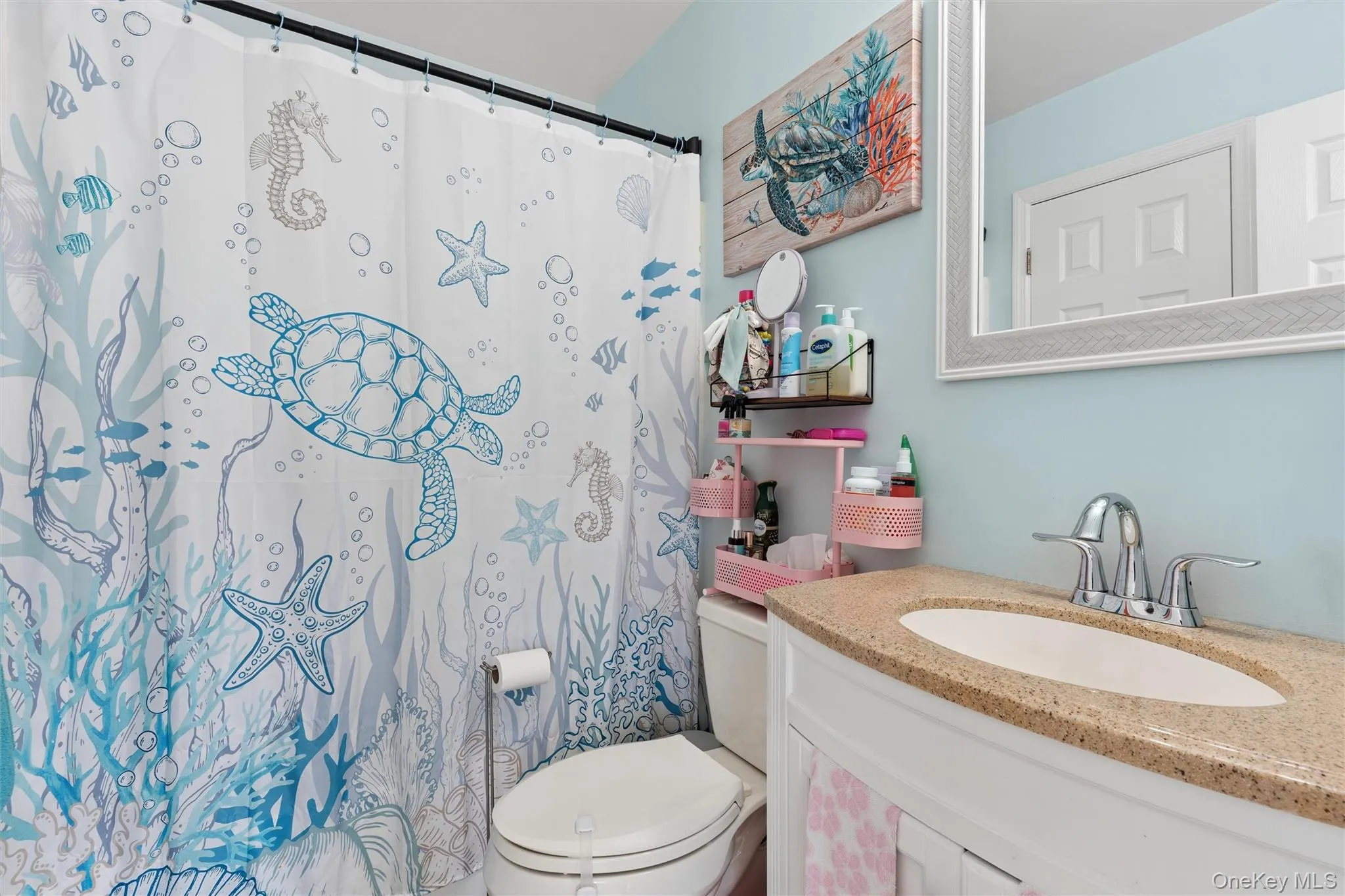 Vanity with a polished chrome faucet, stone-finish countertop, and a framed wall mirror Vanity with a polished chrome faucet, stone-finish countertop, and a framed wall mirror