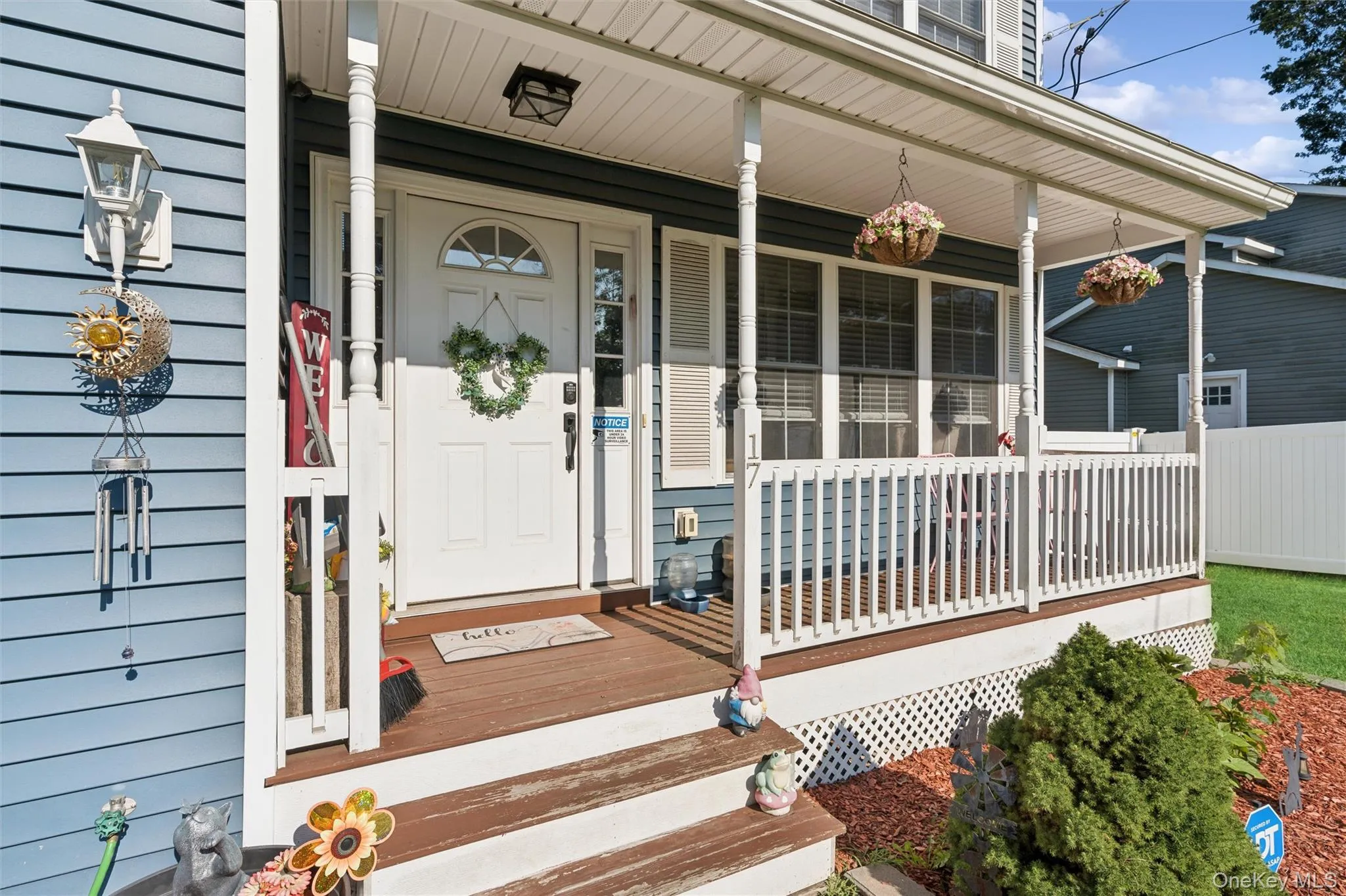 Front porch with wood-finish decking, white railings, and decorative columns Front porch with wood-finish decking, white railings, and decorative columns
