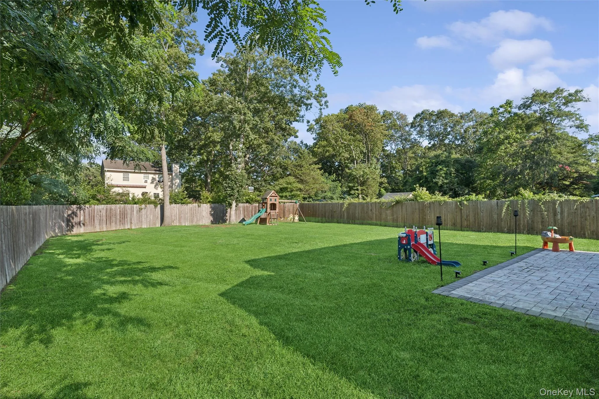 Expansive green lawn, paver patio, and full perimeter wood fencing Expansive green lawn, paver patio, and full perimeter wood fencing