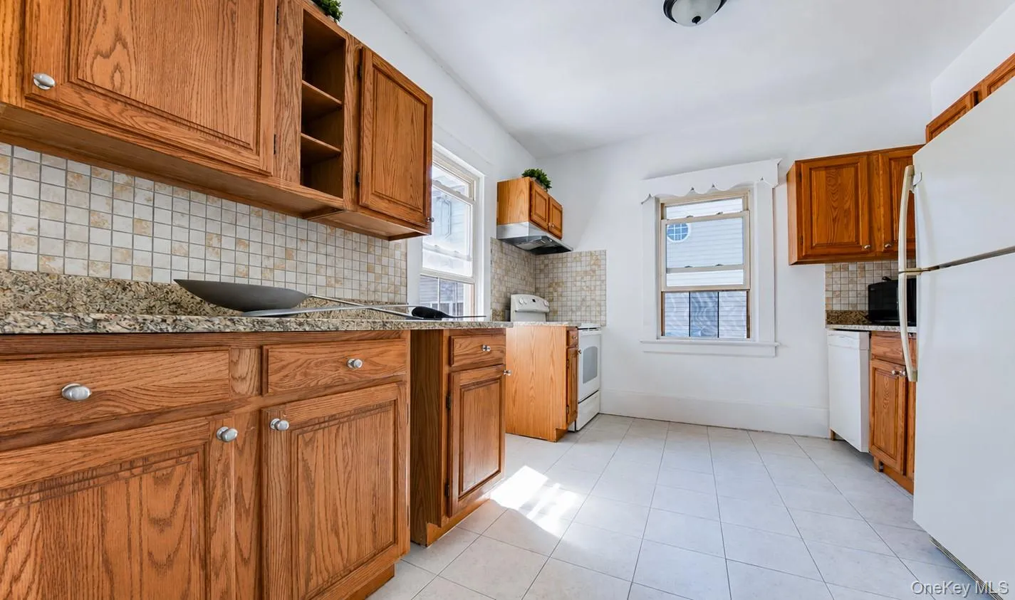 Wood cabinetry, granite-finish countertops, tiled backsplash, and tiled flooring Wood cabinetry, granite-finish countertops, tiled backsplash, and tiled flooring
