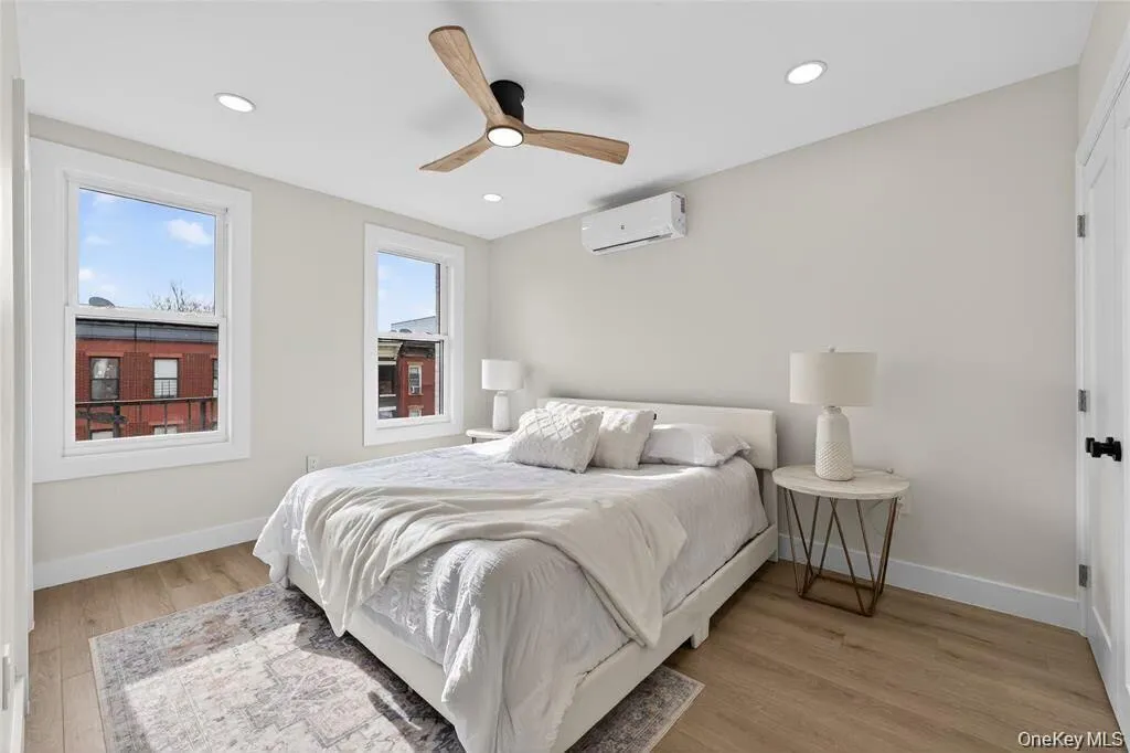 Recessed ceiling lighting, wood-finish flooring, ceiling fan, white trim windows, and wall-mounted climate control unit Recessed ceiling lighting, wood-finish flooring, ceiling fan, white trim windows, and wall-mounted climate control unit