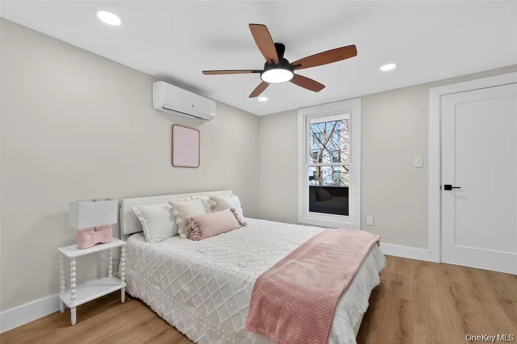 Wood-finish flooring, recessed ceiling lighting, contemporary ceiling fan, mini-split air conditioning unit, and a flat-panel interior door with matte black hardware Wood-finish flooring, recessed ceiling lighting, contemporary ceiling fan, mini-split air conditioning unit, and a flat-panel interior door with matte black hardware