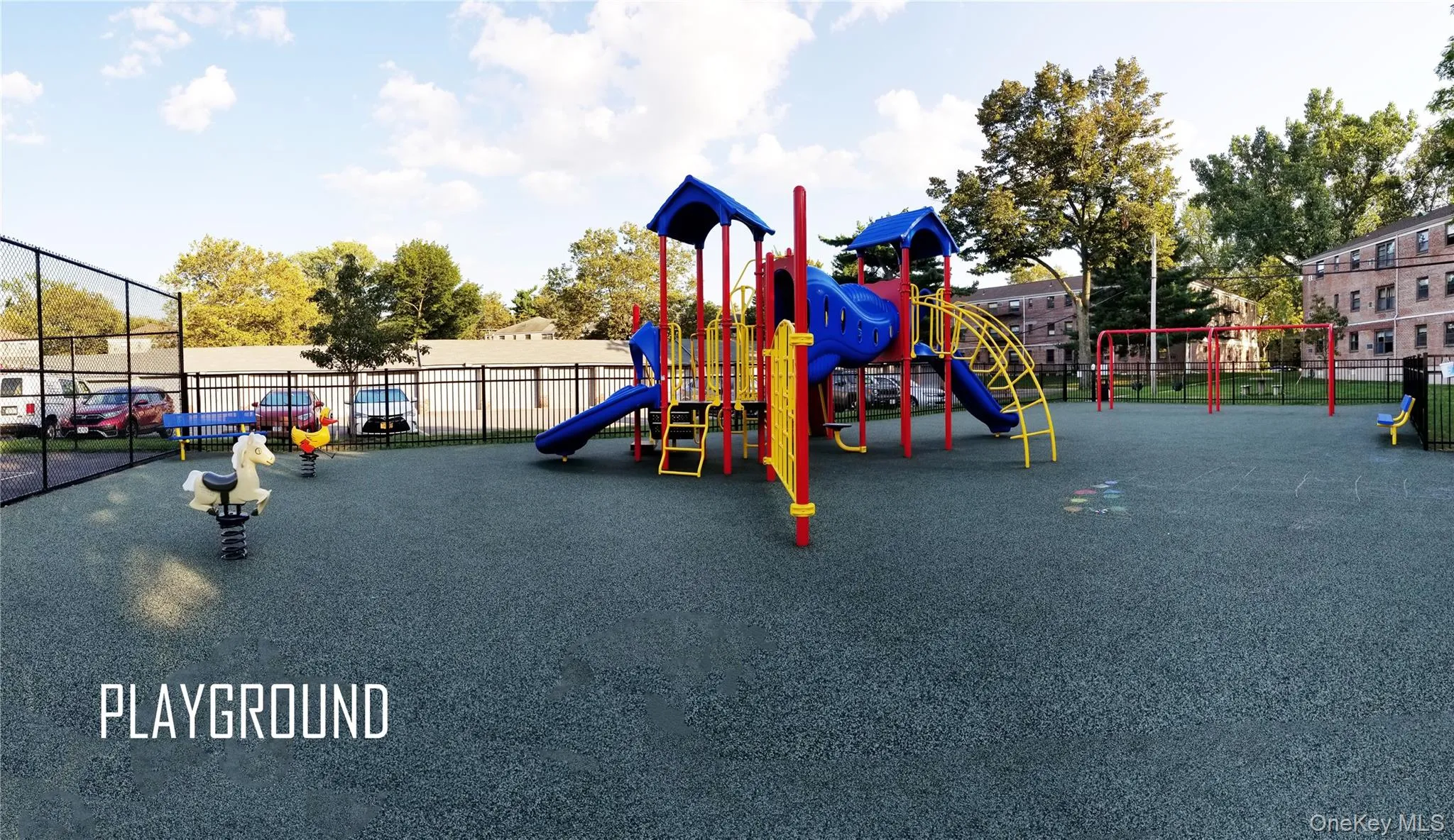 Recreational playground area featuring a composite play structure, swings, and spring riders on a textured ground surface, enclosed by fencing Recreational playground area featuring a composite play structure, swings, and spring riders on a textured ground surface, enclosed by fencing