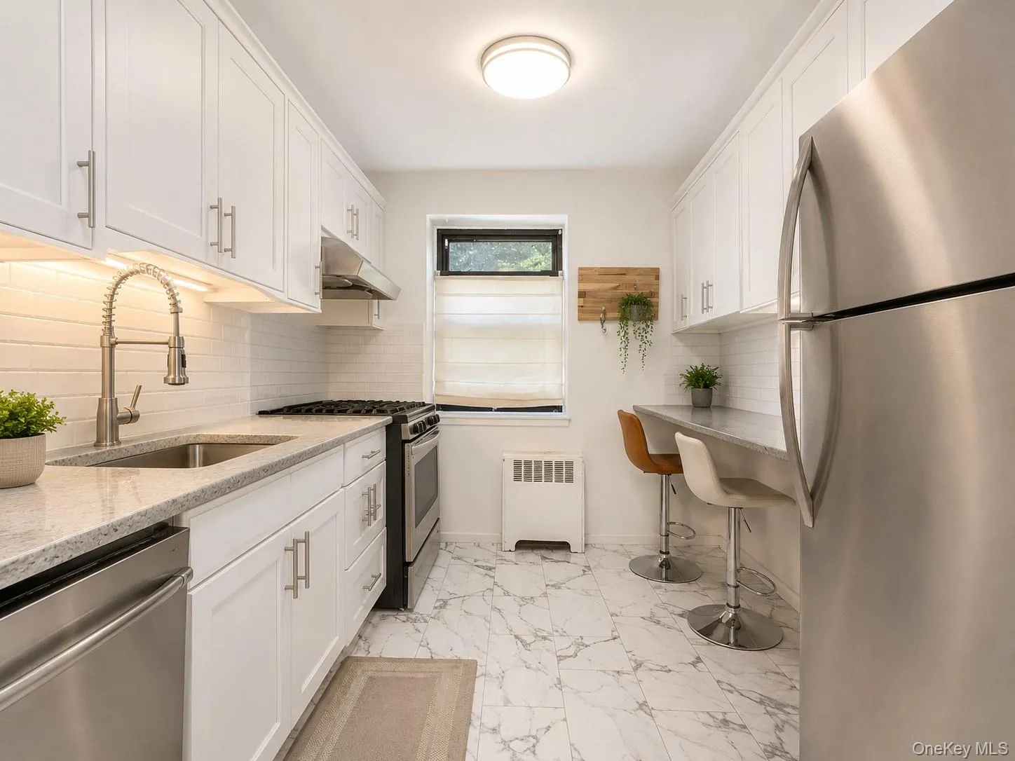 White shaker cabinetry, stainless steel appliances, light-toned countertops, white subway tile backsplash, and marble-look flooring White shaker cabinetry, stainless steel appliances, light-toned countertops, white subway tile backsplash, and marble-look flooring