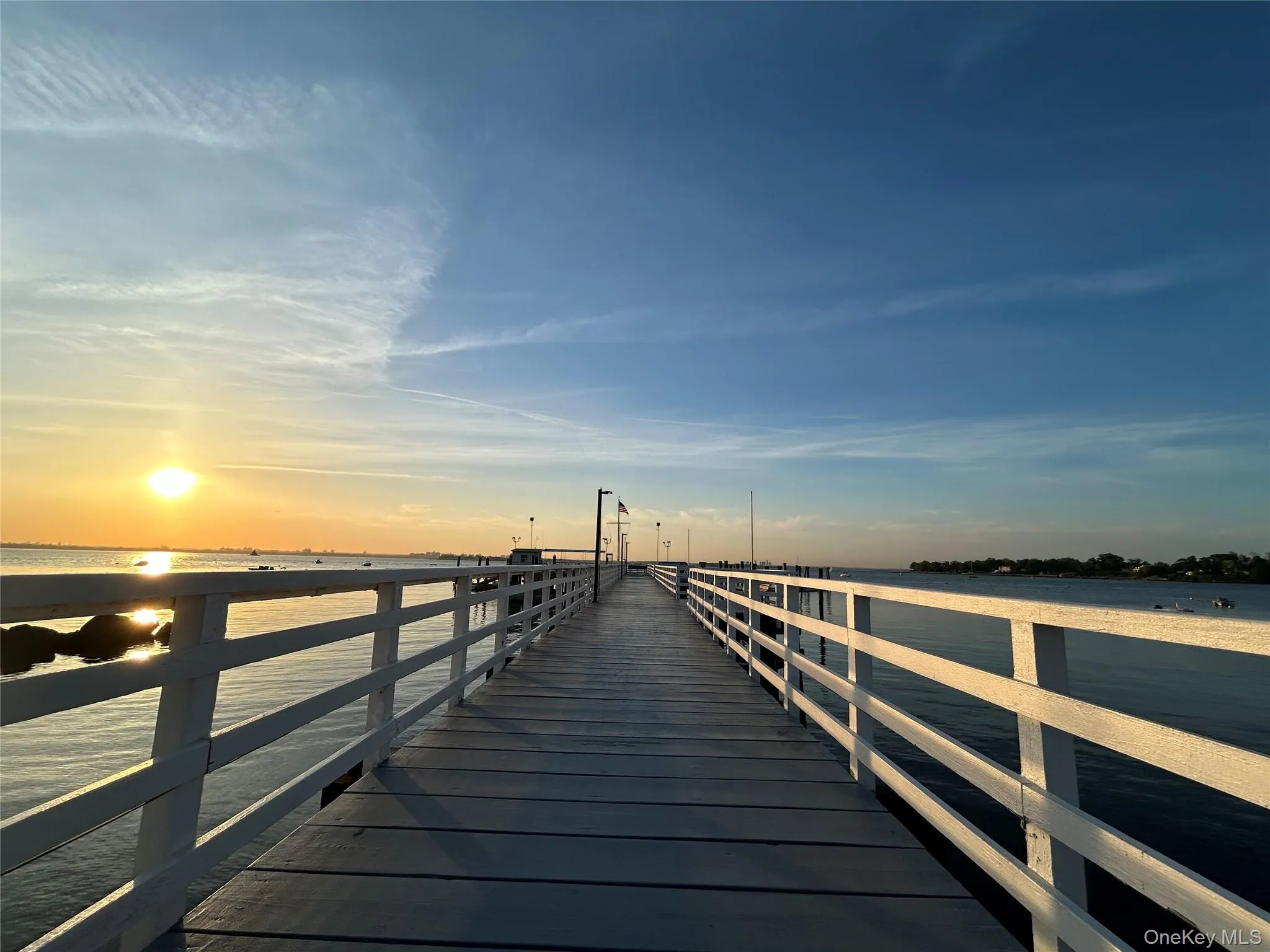 Waterfront pier featuring a wooden deck and white railings Waterfront pier featuring a wooden deck and white railings