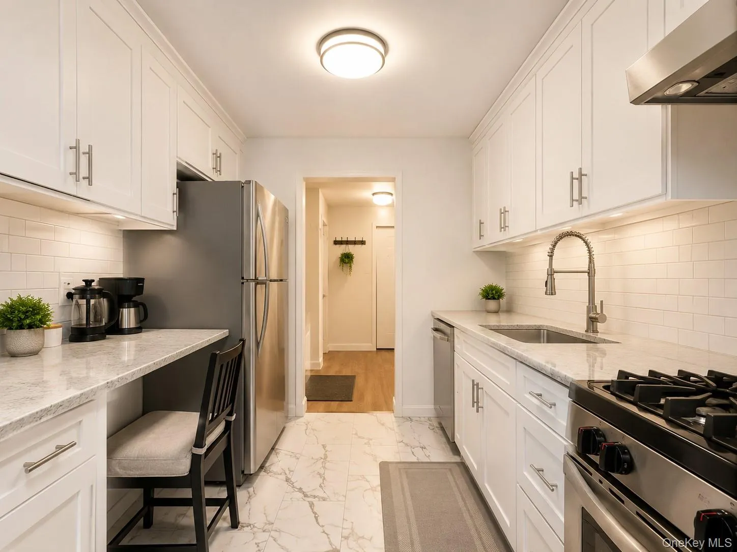 White shaker cabinetry, stainless steel appliances, white subway tile backsplash, white stone countertops, and a built-in desk area White shaker cabinetry, stainless steel appliances, white subway tile backsplash, white stone countertops, and a built-in desk area