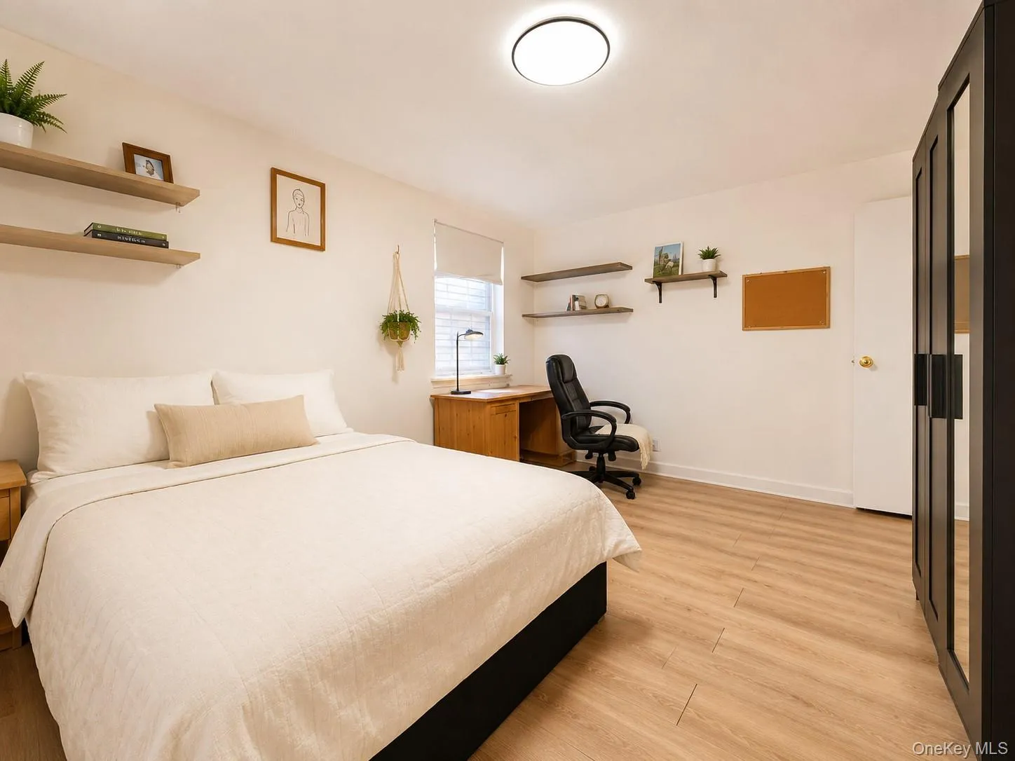 Wood-finish flooring, built-in shelving, flush-mount ceiling light, and a window with roller shade Wood-finish flooring, built-in shelving, flush-mount ceiling light, and a window with roller shade