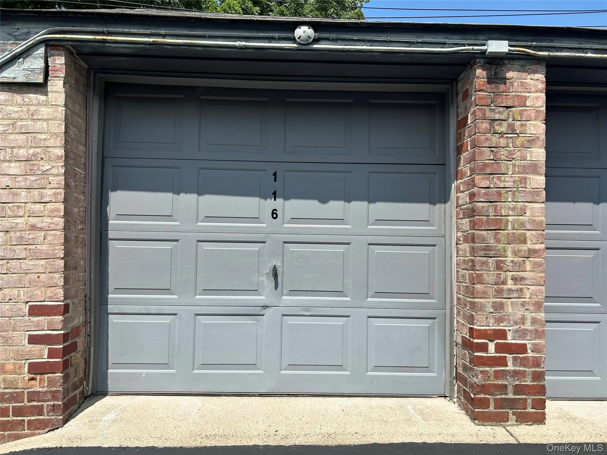 Individual garage bay with a paneled gray door and brick pillar accents Individual garage bay with a paneled gray door and brick pillar accents