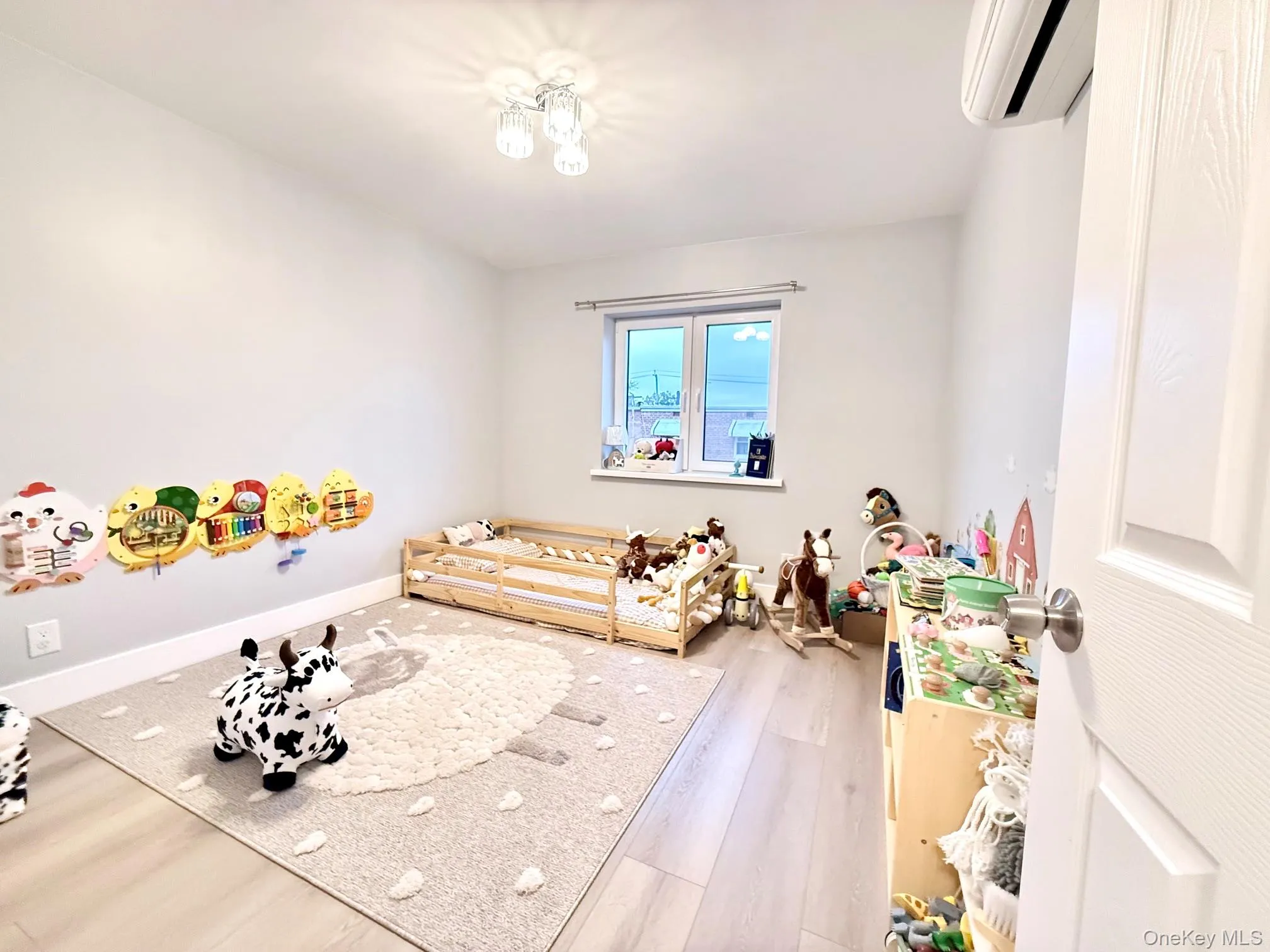 Light-filled room featuring wood-finish flooring, a window with natural light, and a ceiling-mounted light fixture Light-filled room featuring wood-finish flooring, a window with natural light, and a ceiling-mounted light fixture
