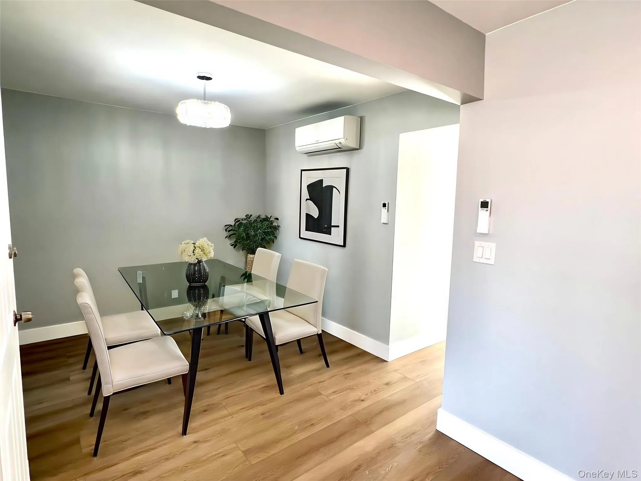 Wood-finish flooring throughout, with a contemporary ceiling light fixture and a wall-mounted air conditioning unit Wood-finish flooring throughout, with a contemporary ceiling light fixture and a wall-mounted air conditioning unit