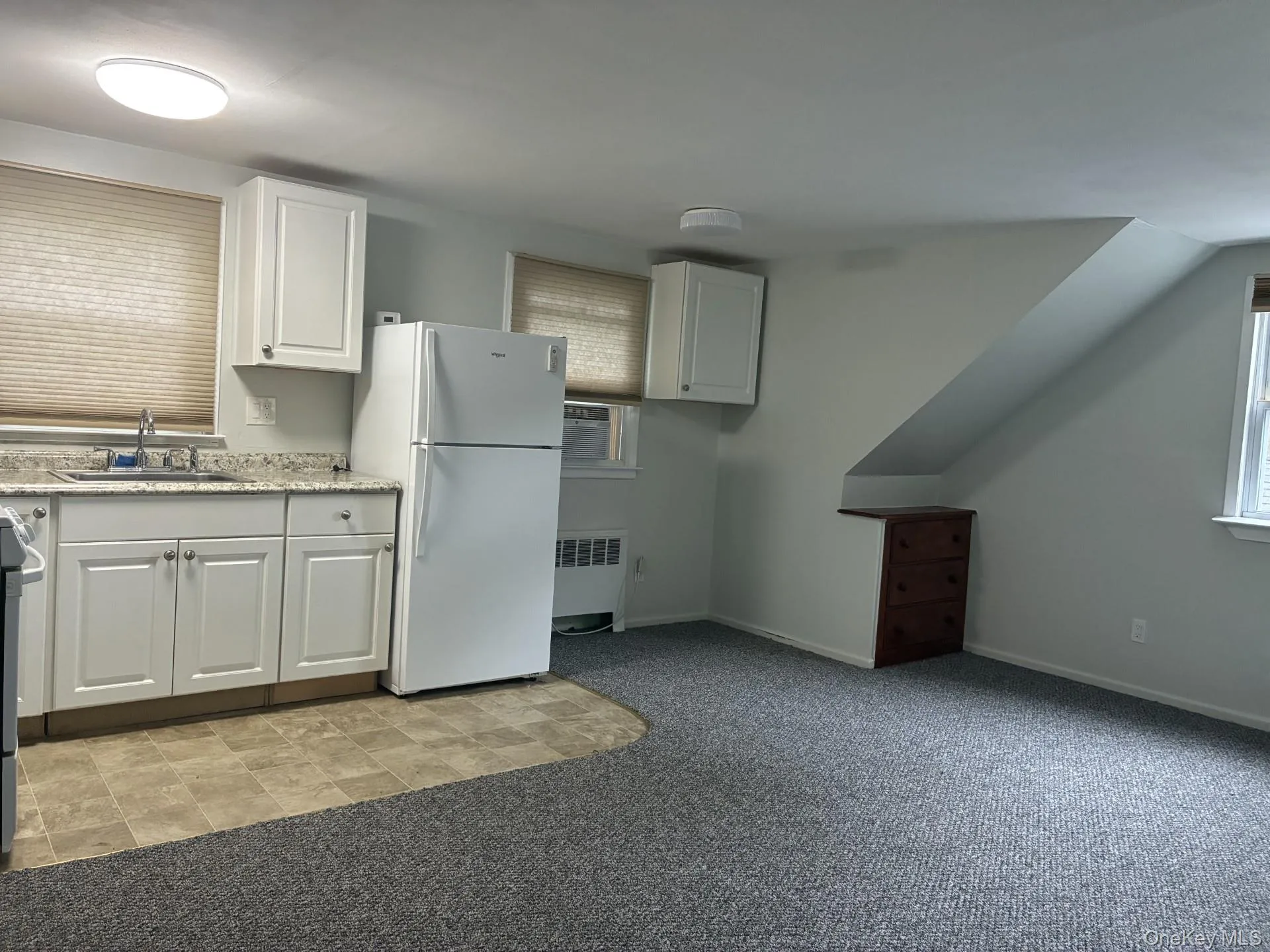 Kitchenette with white cabinetry, stainless steel sink, and light-toned countertops Kitchenette with white cabinetry, stainless steel sink, and light-toned countertops