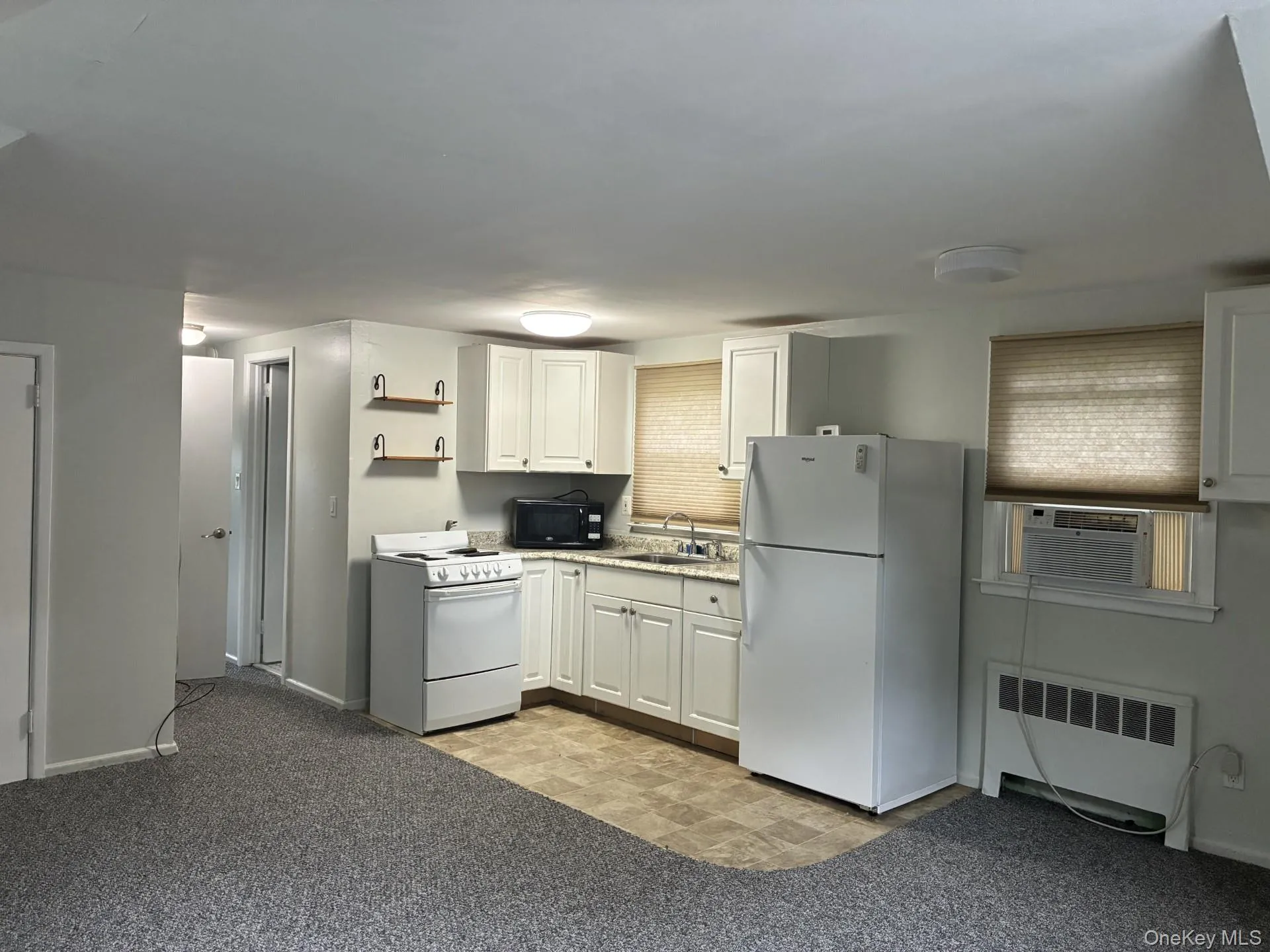 Compact kitchen with white cabinetry, built-in appliances, and light-colored countertops Compact kitchen with white cabinetry, built-in appliances, and light-colored countertops