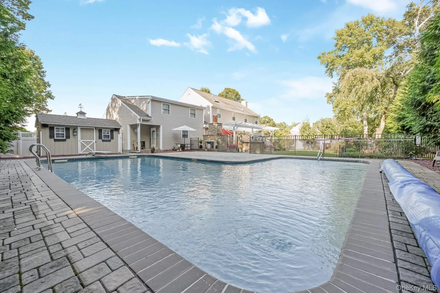 In-ground swimming pool with brick paver surround, accompanied by a detached storage shed In-ground swimming pool with brick paver surround, accompanied by a detached storage shed