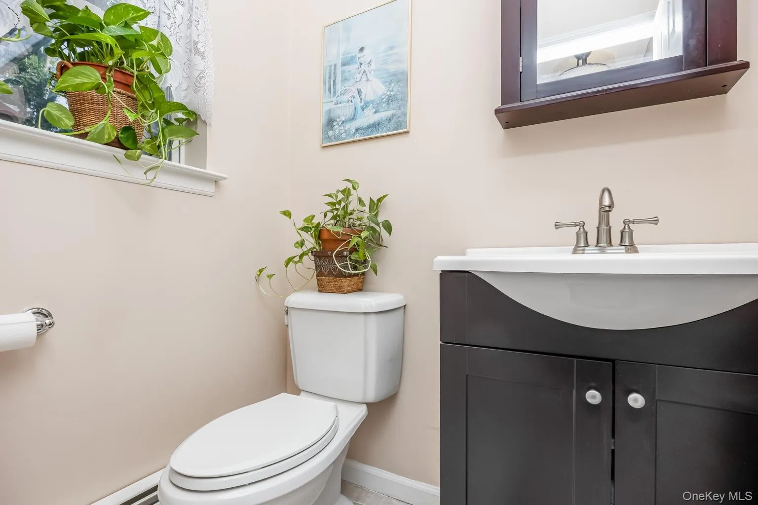 Pedestal sink vanity with dark wood-finish cabinetry, brushed nickel faucet, and a window for natural light Pedestal sink vanity with dark wood-finish cabinetry, brushed nickel faucet, and a window for natural light