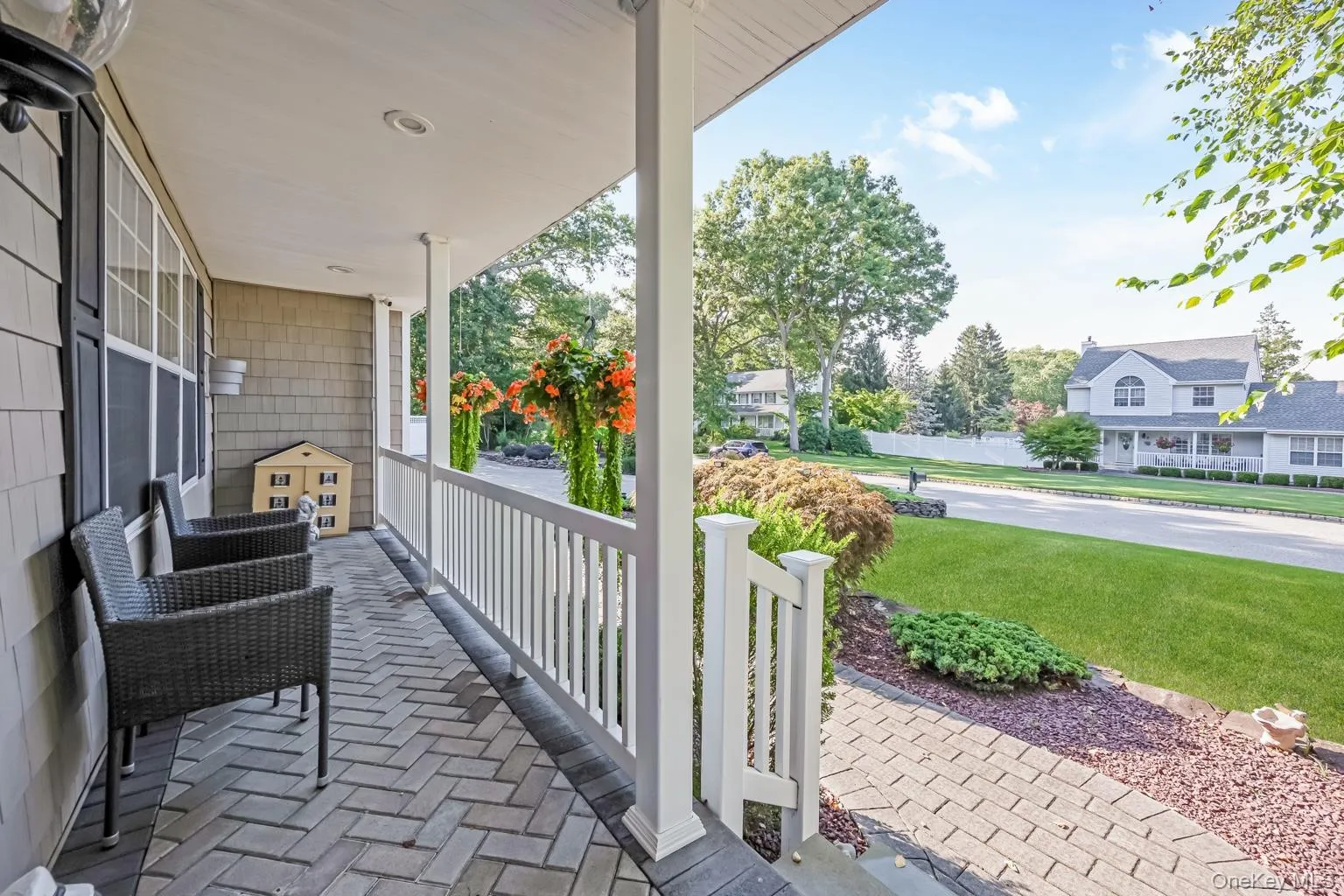 Covered porch with herringbone-patterned paver flooring, white railings, and recessed lighting Covered porch with herringbone-patterned paver flooring, white railings, and recessed lighting