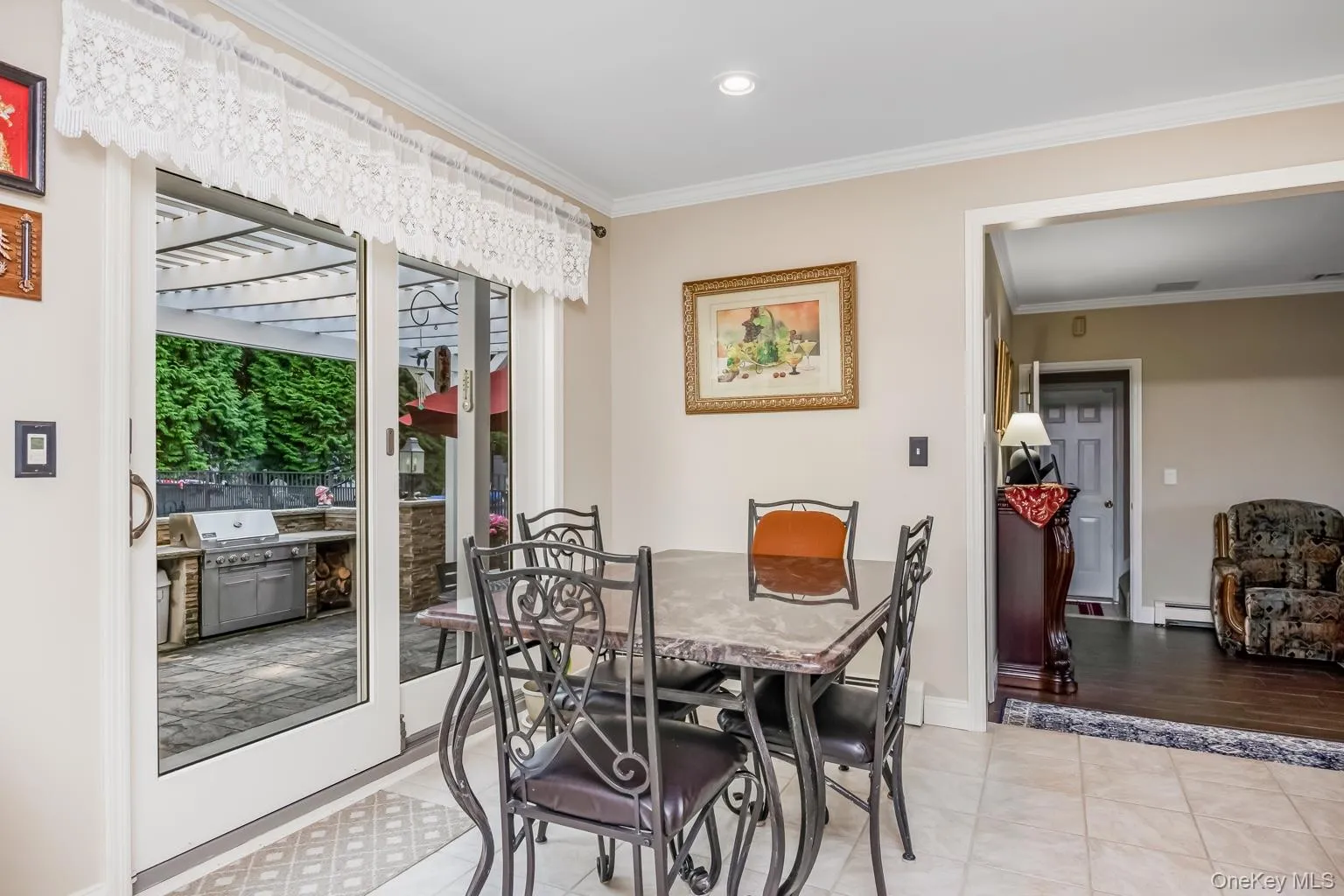 Sliding glass doors opening to a paver patio with a built-in grill station and a pergola Sliding glass doors opening to a paver patio with a built-in grill station and a pergola
