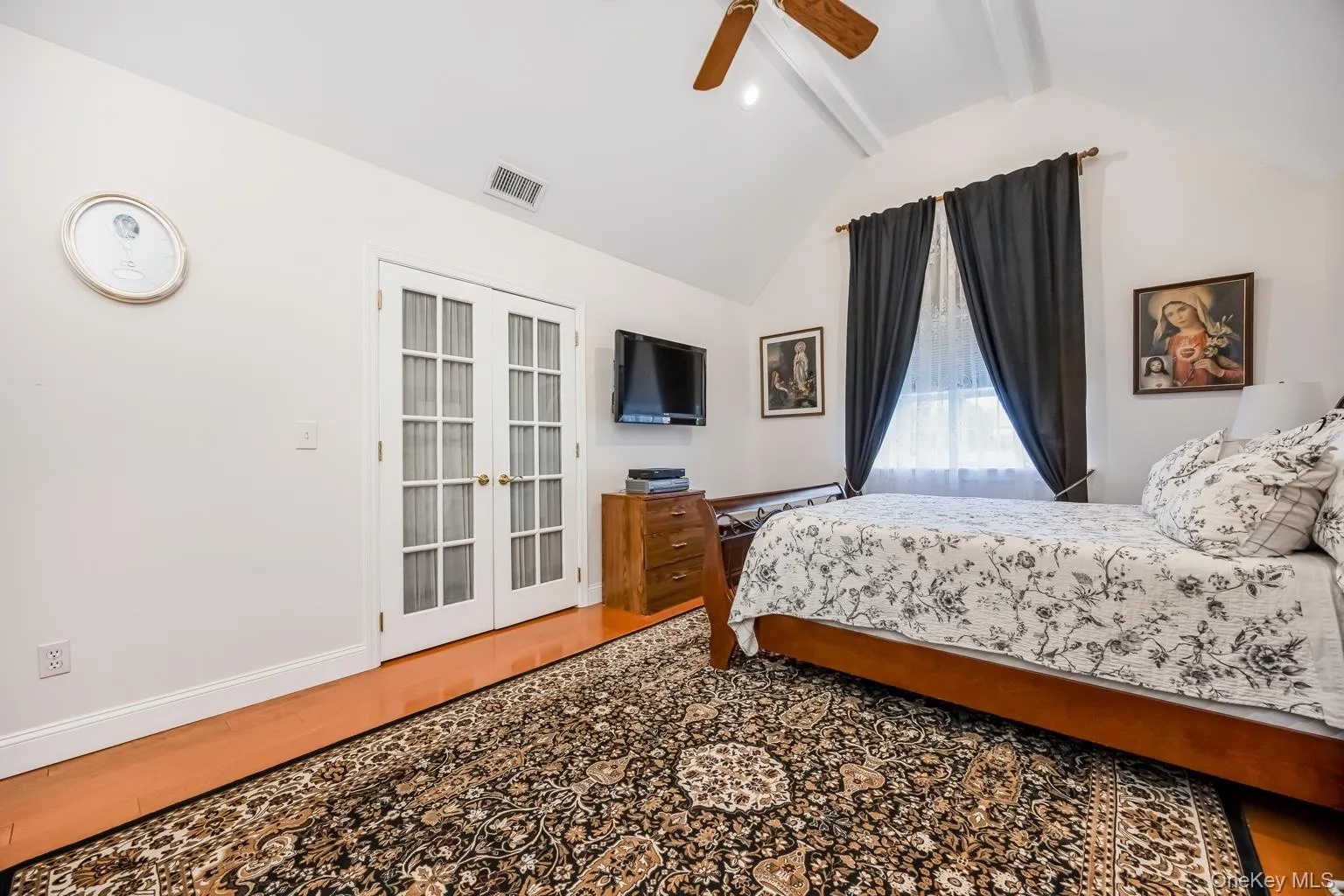Vaulted ceiling with exposed beams, wood-finish flooring, white French doors, and ceiling fan Vaulted ceiling with exposed beams, wood-finish flooring, white French doors, and ceiling fan