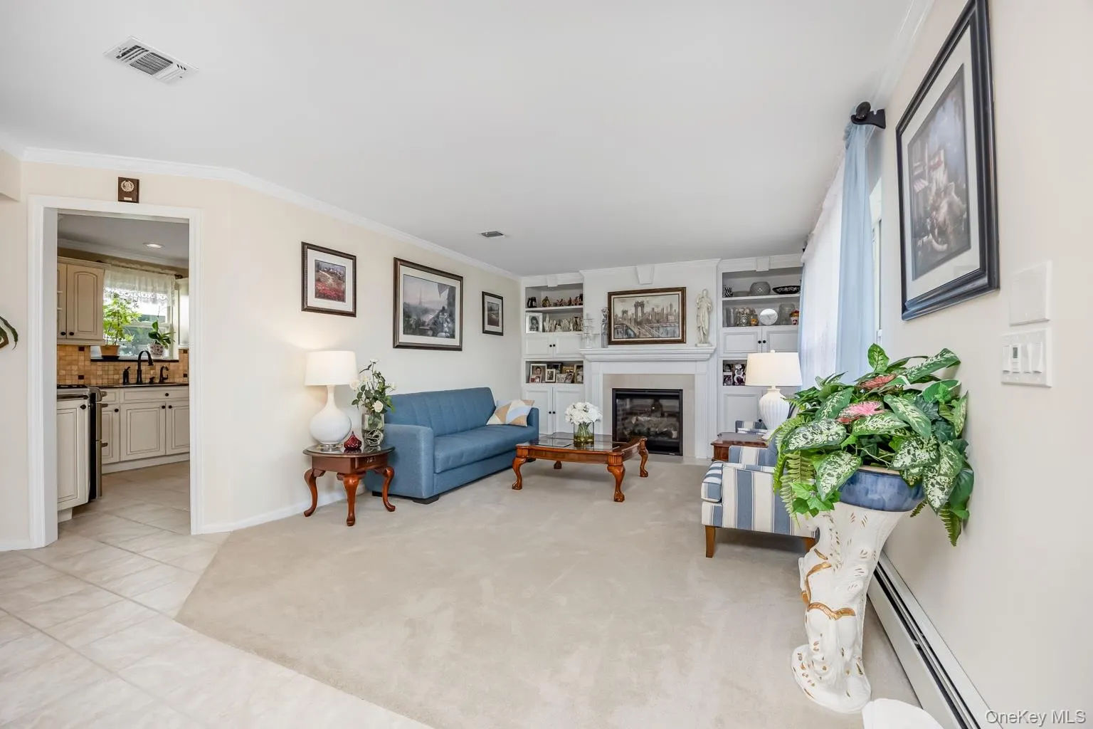 Living space featuring a built-in fireplace, custom shelving, crown molding, and carpeted flooring Living space featuring a built-in fireplace, custom shelving, crown molding, and carpeted flooring