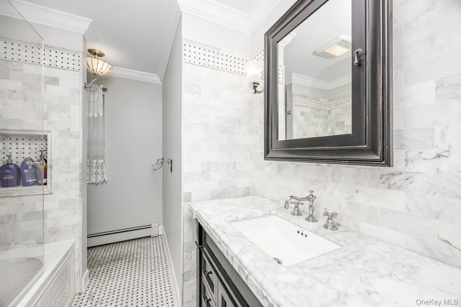 White marble tile walls, black framed mirror, white vanity sink, chrome faucet, and black and white patterned floor tile White marble tile walls, black framed mirror, white vanity sink, chrome faucet, and black and white patterned floor tile