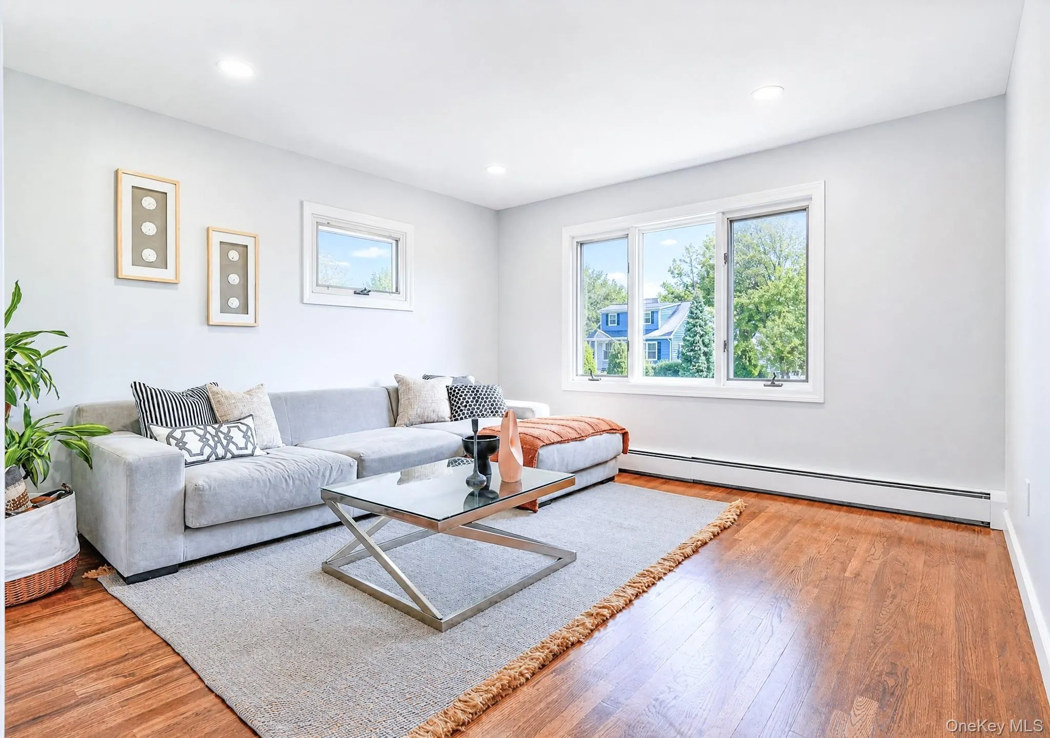 Spacious room featuring wood-finish flooring, white baseboards, and light gray wall paint Spacious room featuring wood-finish flooring, white baseboards, and light gray wall paint