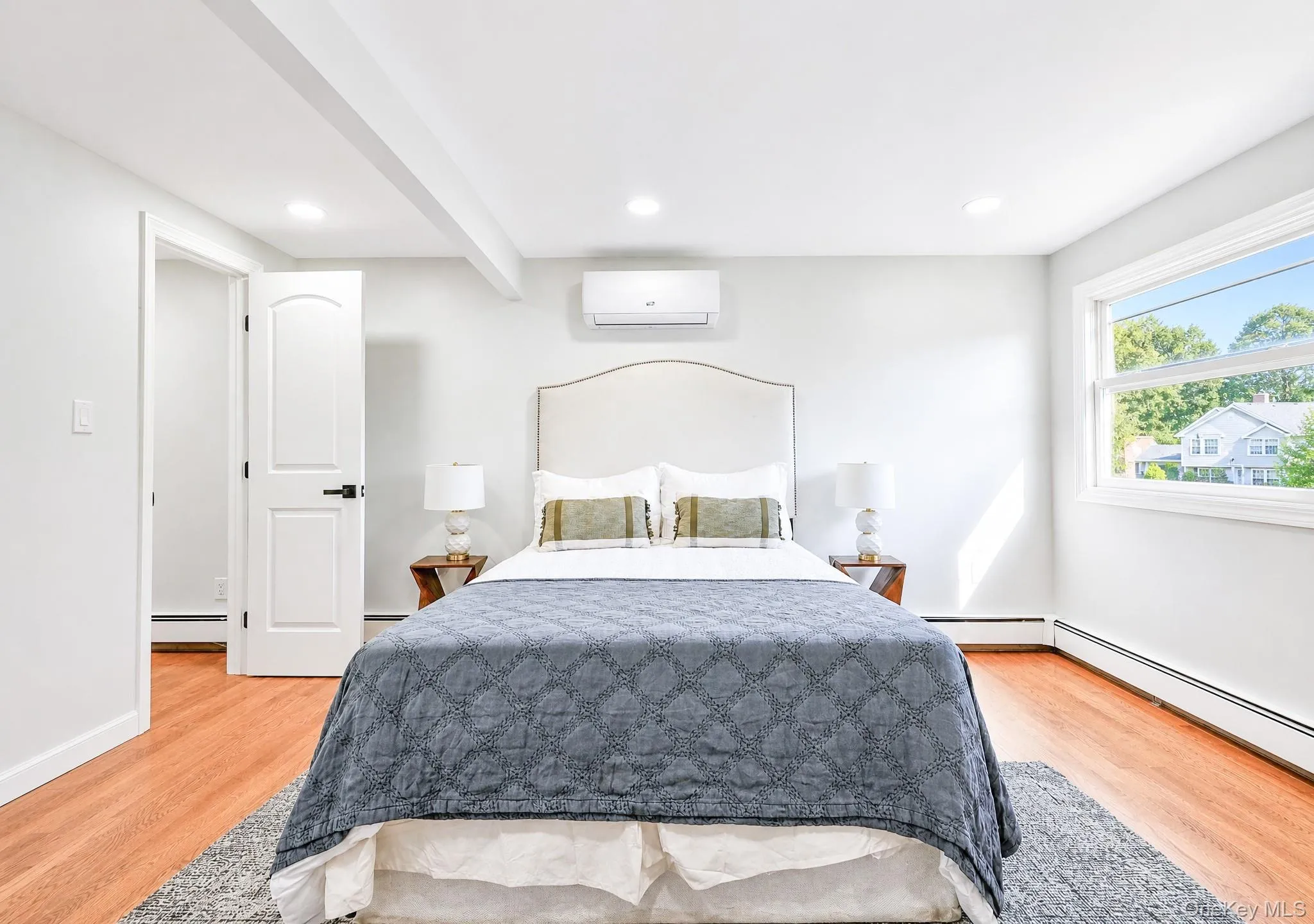 Bedroom featuring wood-finish flooring and a bright window Bedroom featuring wood-finish flooring and a bright window