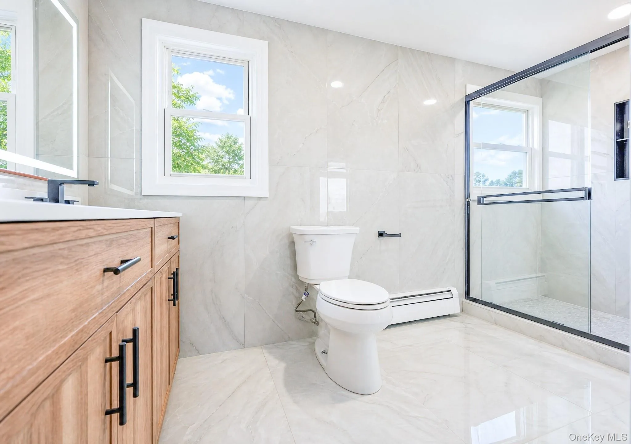 Bathroom featuring a wood-finish vanity with matte black hardware, white rectangular sink, and wall-mounted faucet Bathroom featuring a wood-finish vanity with matte black hardware, white rectangular sink, and wall-mounted faucet